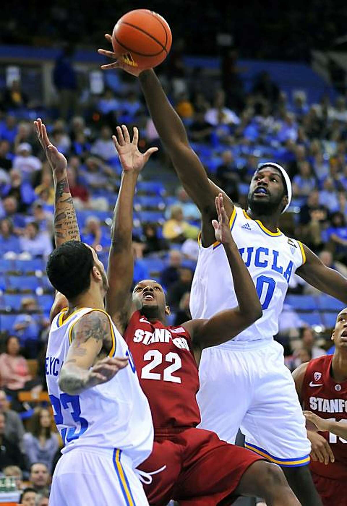 Stanford's Jarrett Mann (22) has his shot blocked as he tries to shoot between UCLA's Anthony Stover, right, and Tyler Honeycutt in the first half of an NCAA college basketball game, Saturday, Jan. 22, 2011, in Los Angeles.