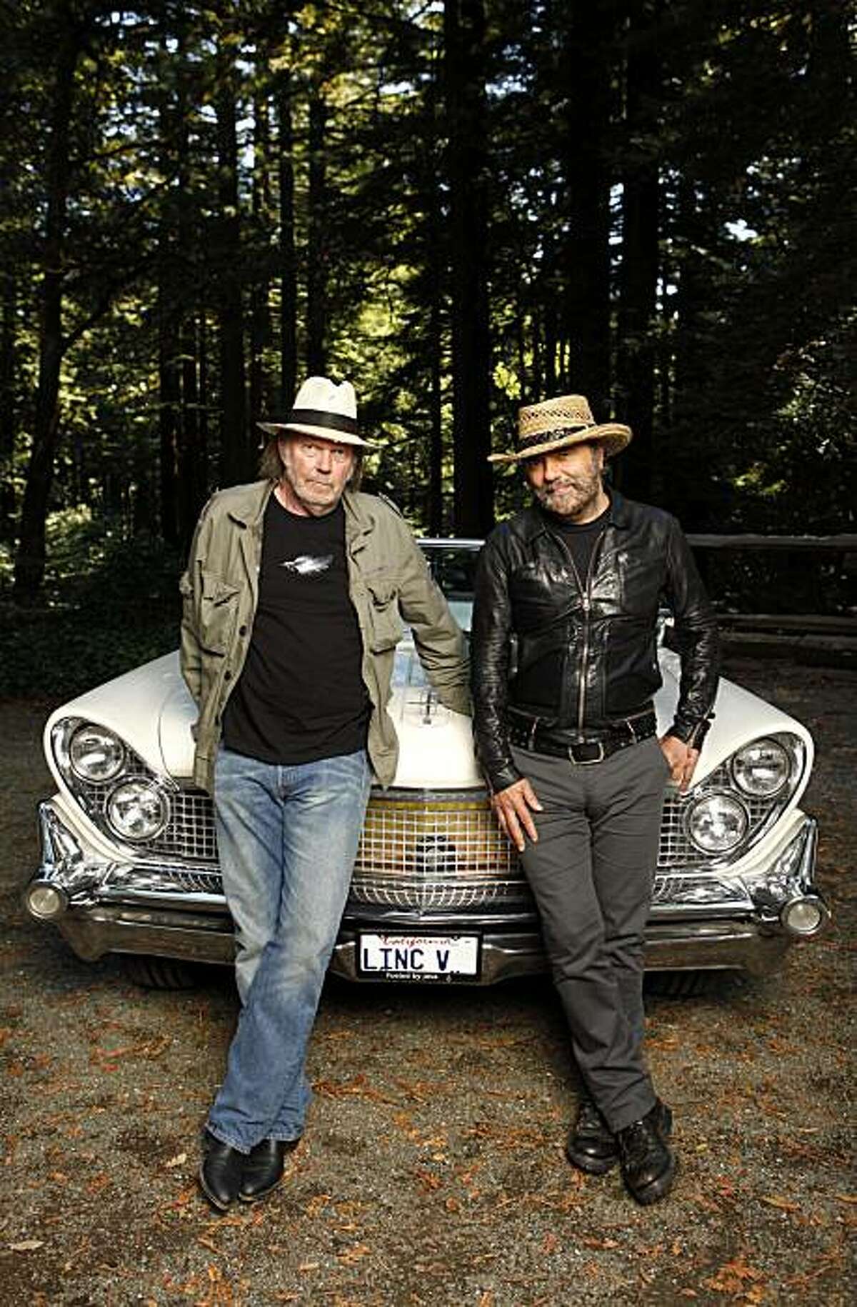 In this Sept. 10, 2010 file photo, musicians Neil Young, left, and Daniel Lanois are photographed beside Young's 1959 hybrid Lincoln Continental in Woodside, Calif. A fire at a San Francisco Bay area warehouse that stored memorabilia belonging toNeil Young started the vintage car the singer had converted into a hybrid vehicle. Belmont-San Carlos Fire Marshal Jim Palisi told the San Mateo County Times the Nov. 9 fire began in Young's 1959 Lincoln Continental and then spread to the nearby warehouse. Young had converted the car to run on electric batteries and a biodiesel-powered generator as part of the LincVolt project.
