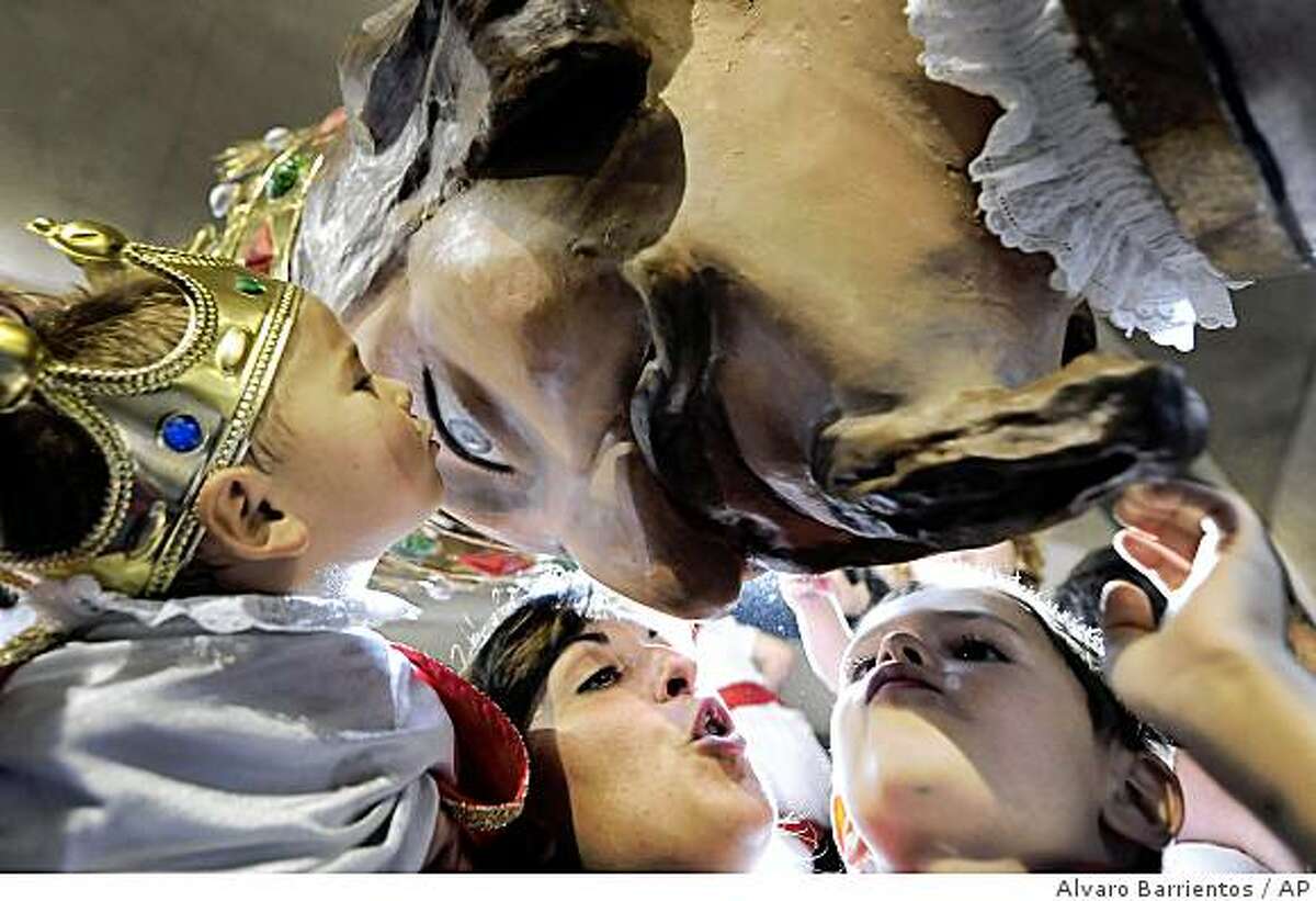 Children kiss the figure of the King of the Parade of the giants and big heads, or 'Comparsa de Gigantes y Cabezudos', at the end of the San Fermin Festival where they danced through the streets of Pamplona, northern Spain, Tuesday, July 14, 2009. The fiestas 'Los San Fermines' held since 1591, attracts tens of thousands of foreign visitors each year for nine days of revelry, morning bull-runs and afternoon bullfights. (AP Photo/Alvaro Barrientos)