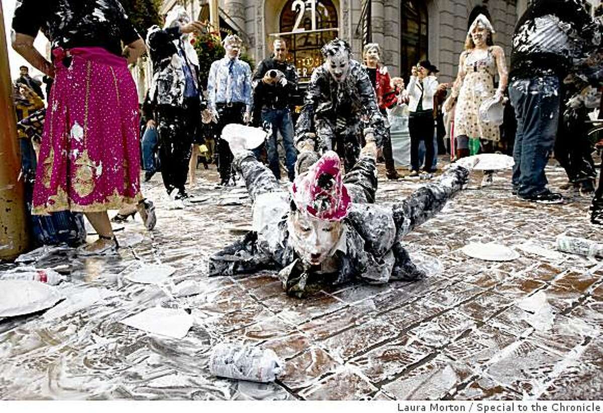 Lee Harvey Roswell pulls Anne-Marie Goco through the sidewalk covered in shaving cream during a flash mob pie fight at the Powell and Market cable car turn around in San Francisco, Calif., on Thursday, March 5, 2008.