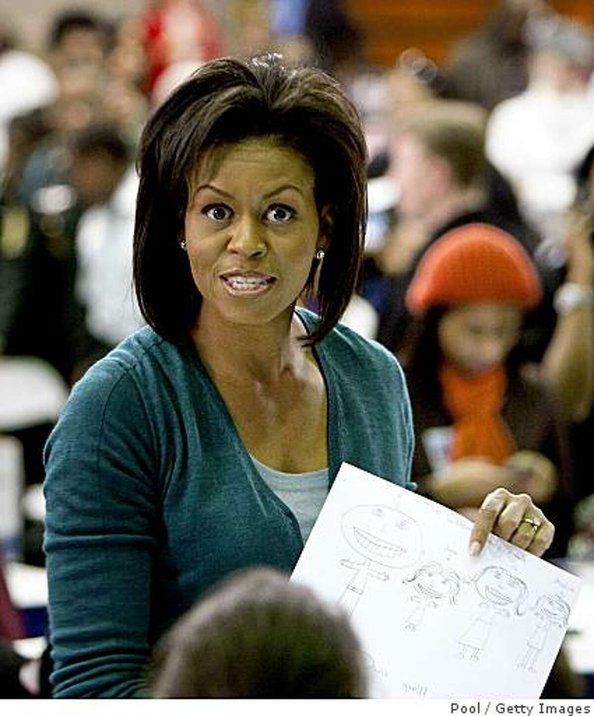 WASHINGTON - JANUARY 19: Michelle Obama holds a picture a young girl drew of her family at Calvin Coolidge High School where students, military families, and volunteer service groups are working on various projects supporting the troops on January 19, 2009 in Washington, DC. Obama stopped at Calvin Coolidge High School to promote his "Day of Service" program. (Photo by Joshua Roberts-Pool/Getty Images)