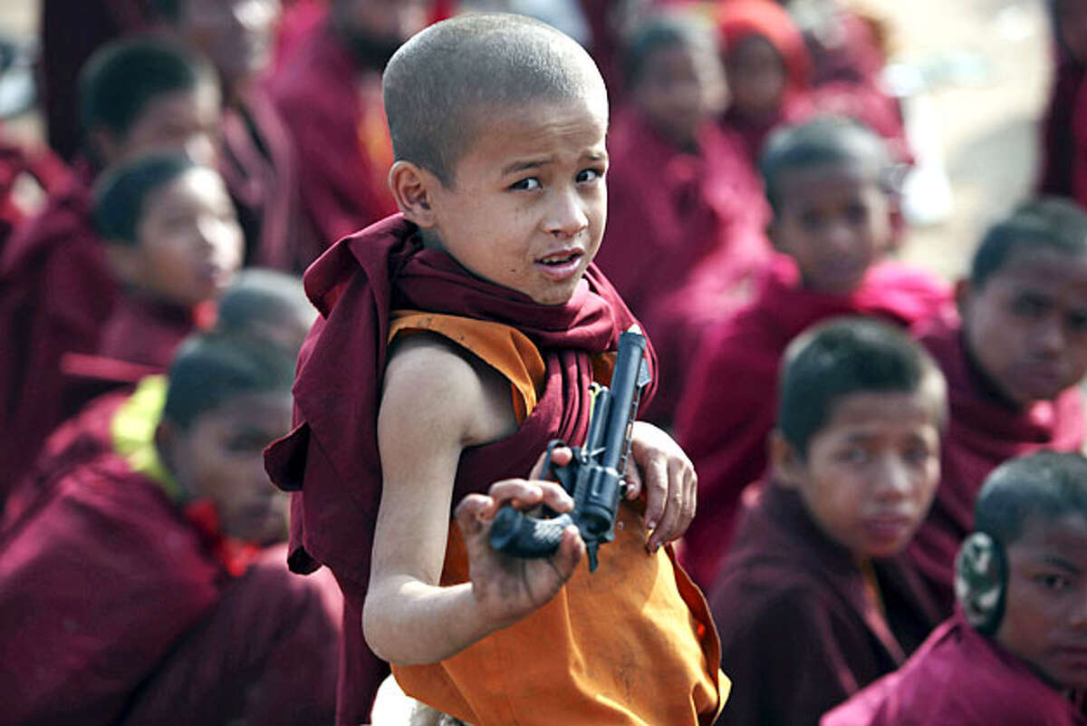 A young Indian Buddhist monk holds a toy gun as he and others listen to the Dalai Lama's lecture at Mahabodhi temple in Bodh Gaya, about 130 kilometers (81 miles) south of Patna, India, Friday, Jan. 8, 2010. Bodh Gaya is the town where Prince Siddhartha Gautama attained enlightenment after intense meditation and became the Buddha. The lectures will continue till Saturday.