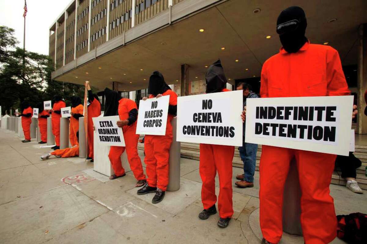 Human rights activists wearing orange jumpsuits and black hoods, mark the 10th anniversary of the U.S. naval base at Guantanamo Bay, Cuba being used as a detention facility in the "war on terror,'' outside the Los Angeles Federal Building in Los Angeles Wednesday, Jan. 11, 2012. (AP Photo/Damian Dovarganes)