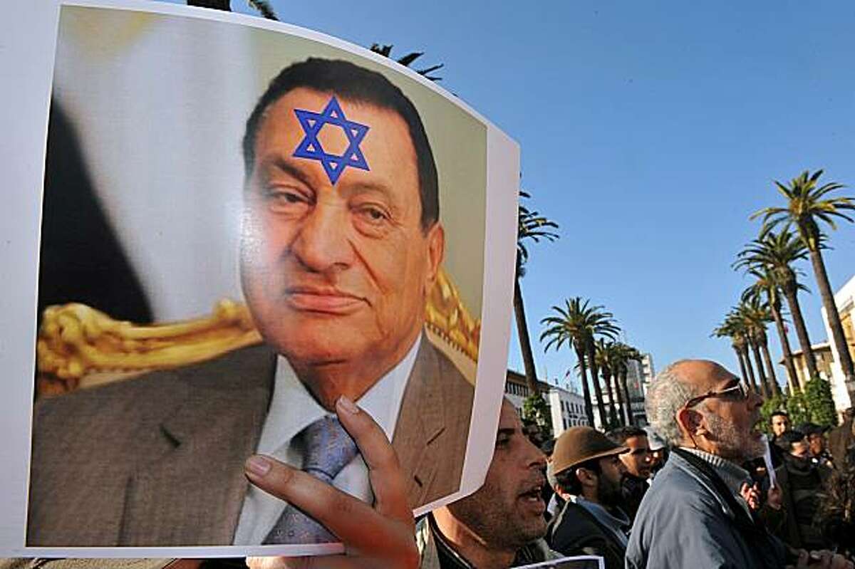 A woman holds a poster showing Egyptian president Hosni Mubarak with the David Star on his forehead while around 300 people stand in front of the parliament in Rabat on February 12, 2011 during a demonstration called by Oussama Lakhlifi on Facebook to celebrate the fall of Egyptian president Hosni Mubarak. Lakhlifi has also posted a call on Facebook for a demonstration to ask more social justice in Morocco on February 20, 2011.