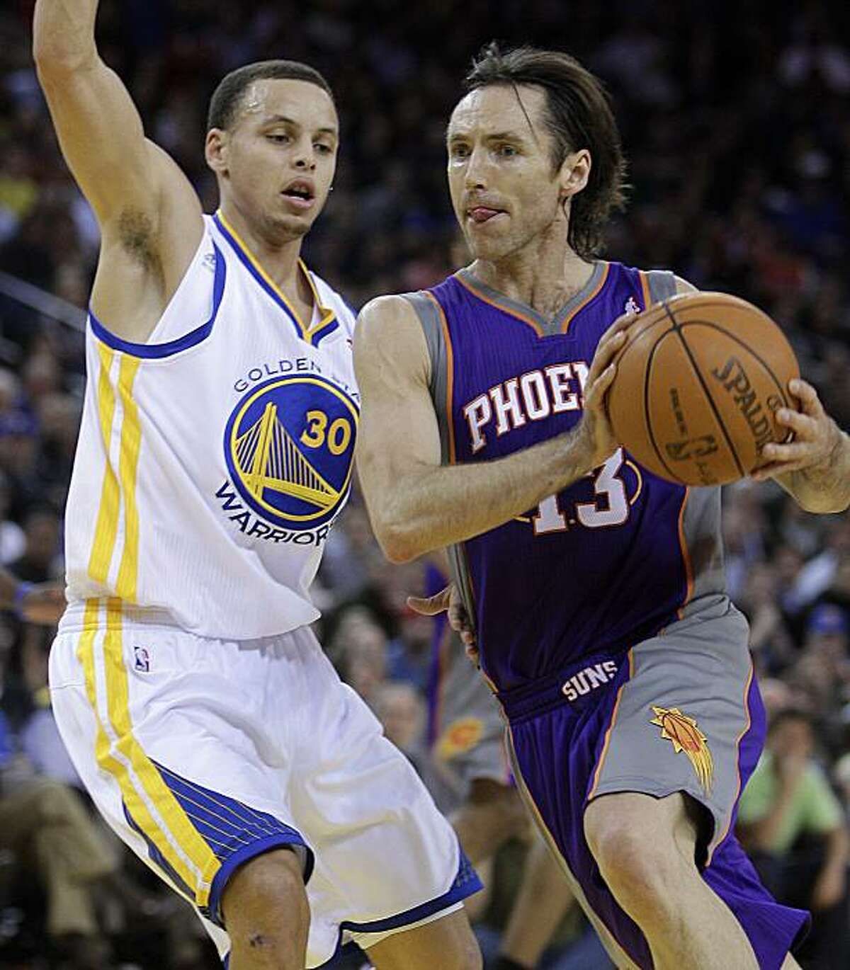 Phoenix Suns' Steve Nash, right, drives to the basket as Golden State Warriors' Stephen Curry defends during the first half of an NBA basketball game Monday, Feb. 7, 2011, in Oakland, Calif.