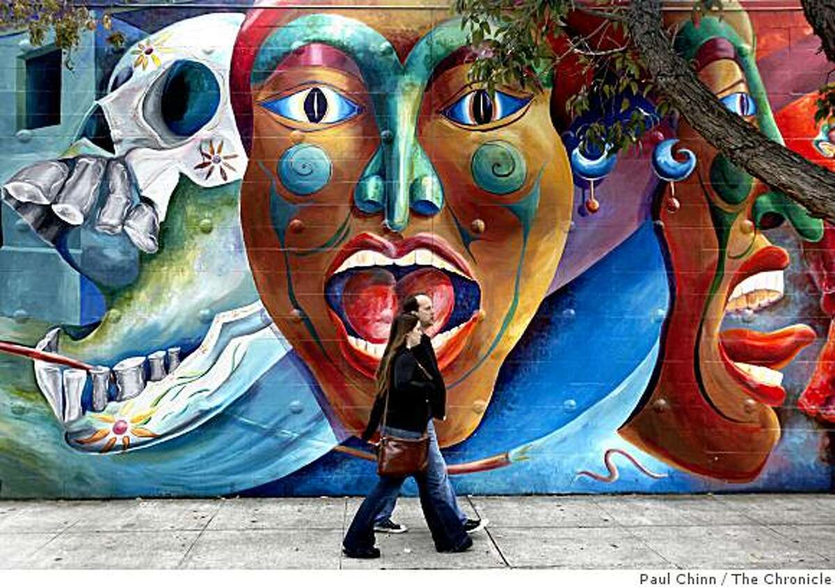 A couple walks past a Carnaval mural painted by the Precita Eyes Muralists on Harrison Street in San Francisco, Calif., on Saturday, May 23, 2009.