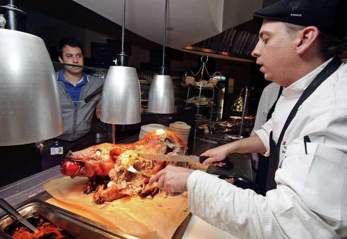 Stephen Paprocki, right, Head Chef at the dining cafeteria at Security Service Federal Credit Union serves up a plate of Honey Hoisin Whole Roasted Pig to Rene Martinez, Wednesday, Jan. 11, 2012. Photo Bob Owen/rowen@express-news.net