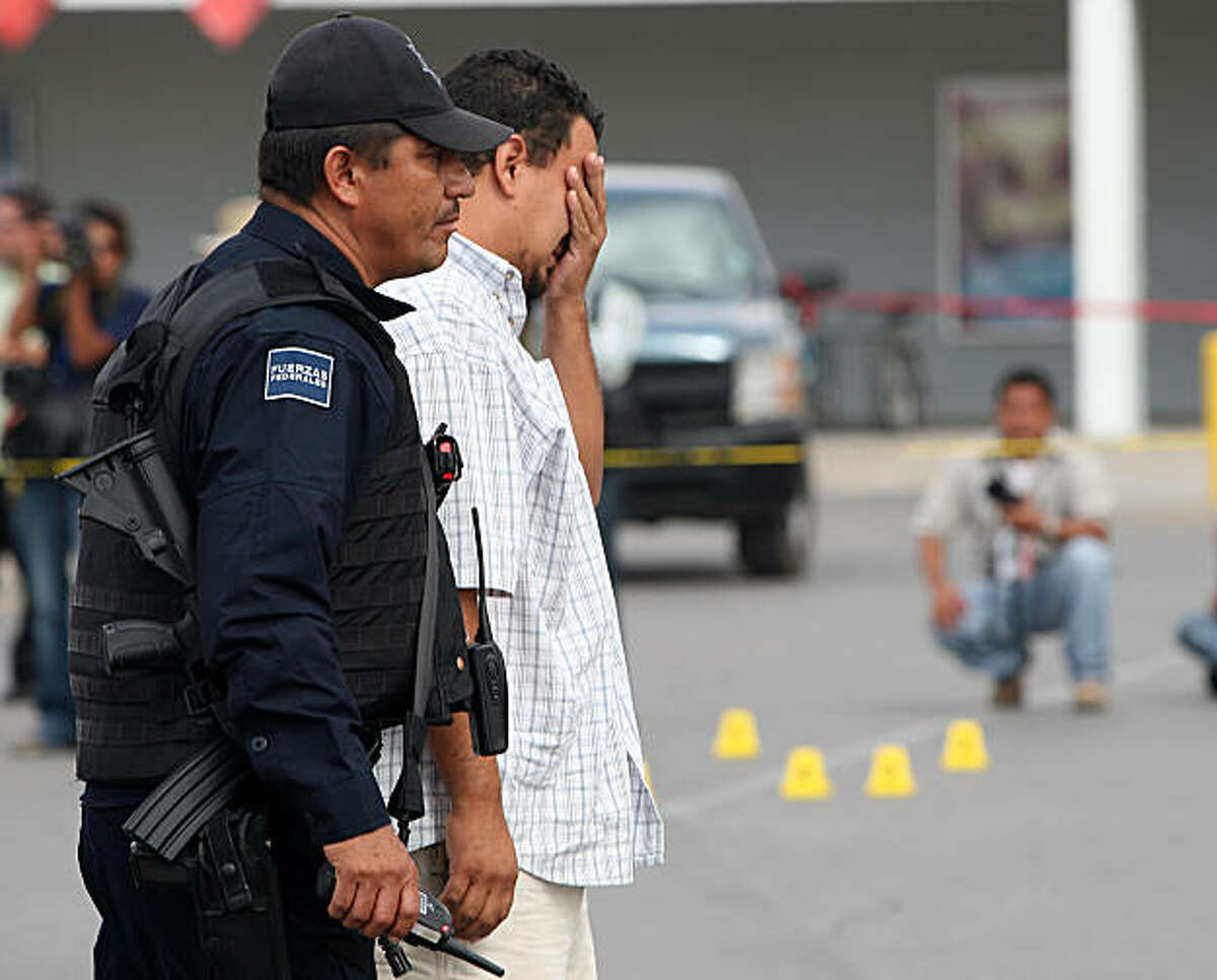A relative of photojournalist Luis Carlos Santiago, of El Diario newspaper, who was killed by gunmen in a parking lot in Mexico's most dangerous city of Ciudad Juarez, on the US border, cries next to a policemen at the scene of the crime on September 16,2010. A colleague of Santiago from the same newspaper was seriously hurt in the attack.