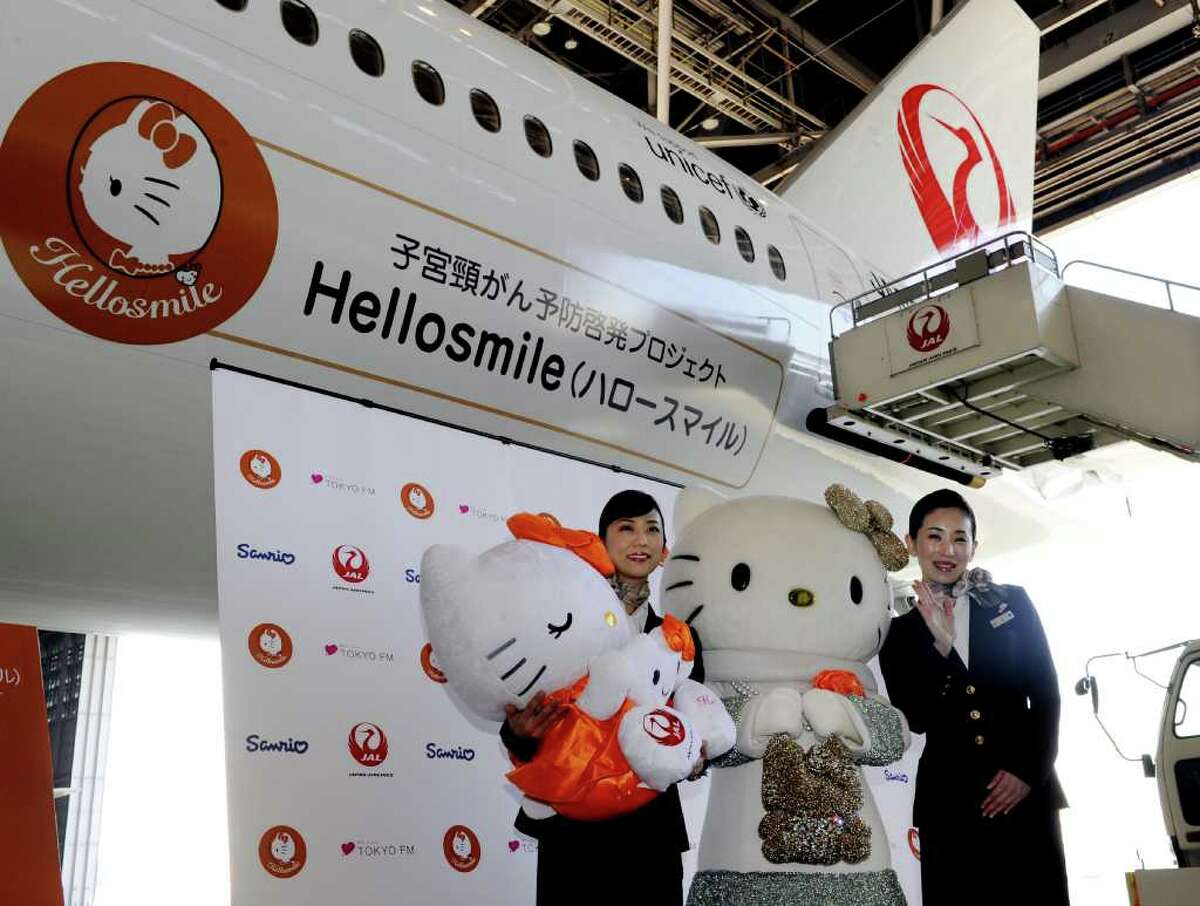 Japan Airlines (JAL) cabin attendants and Sanrio character Hello Kitty introduce Japan Airlines' Hellosmile jet, a Boeing 777 jetliner painted with a Hello Kitty face to raise awareness of cervical cancer, at JAL's hanger at the Haneda airport in Tokyo on january 13, 2012. Hello Kitty, which started in 1974 in Japan as a moon-faced cartoon cat on a coin purse, has developed into a global phenomenon. AFP PHOTO / Yoshikazu TSUNO