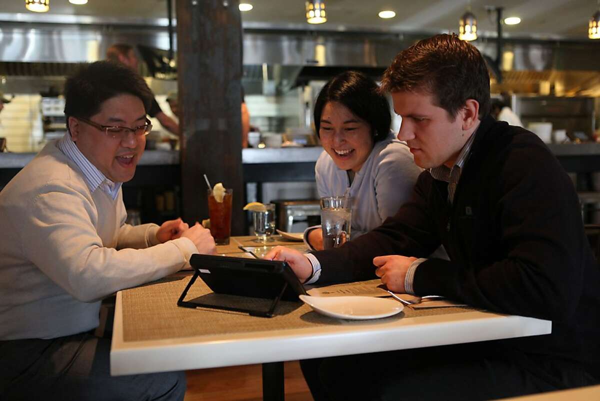Sidney Chen (far left), Cindy Matsuyama (middle), and Ivan Tsurikov (right) look over a new tablet that restaurants can put at every table for do-it-yourself ordering, paying the bill, and playing games while at Calafia in Palo Alto, Calif., on Wednesday, January 11, 2012.