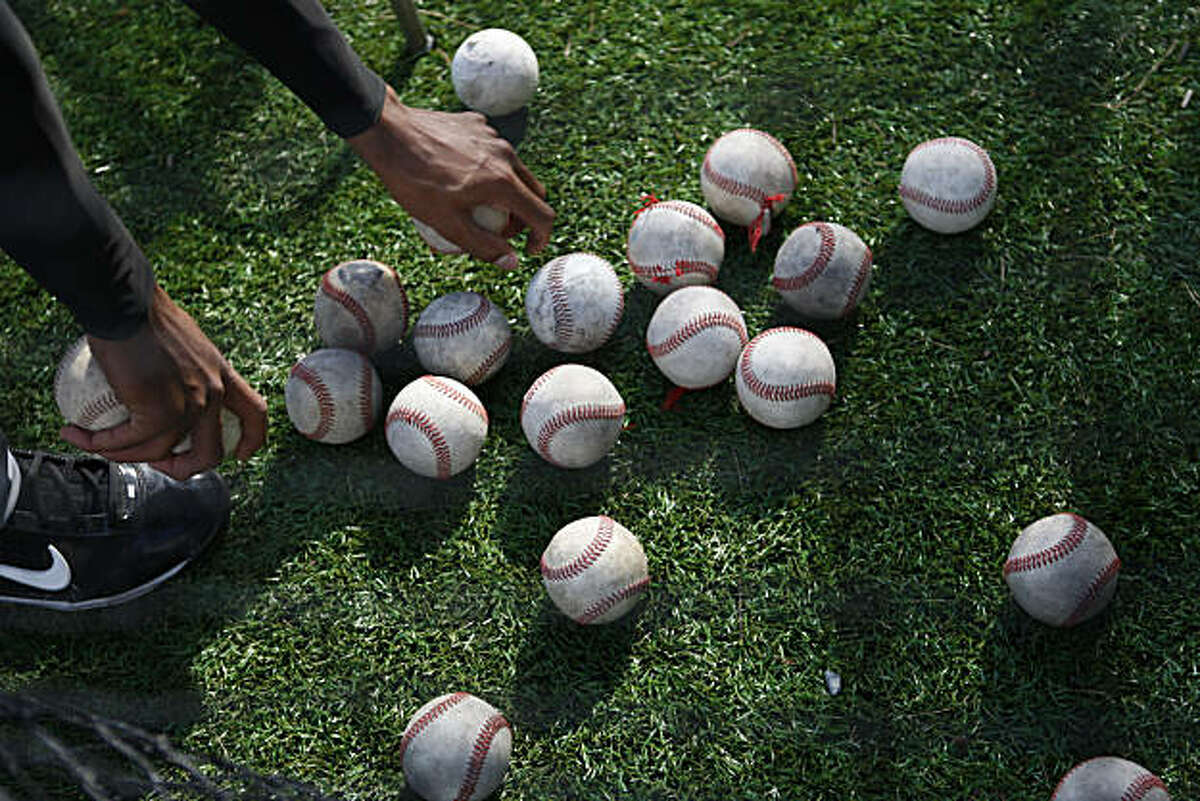 A City College of San Francisco baseball player picks up balls during the team's batting practice in Pacifica Calif, on Tuesday, Feb. 22, 2011.