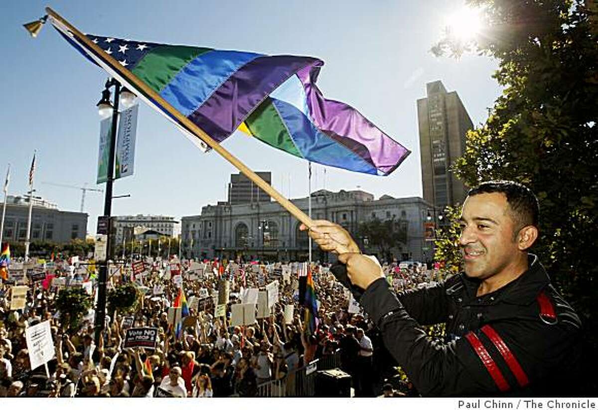 Alexander Sanchez waves a stars and rainbow stripes flag in front of thousands attending a rally at City Hall to protest the passage of the Proposition 8 marriage initiative in San Francisco, Calif., on Saturday, Nov. 15, 2008.