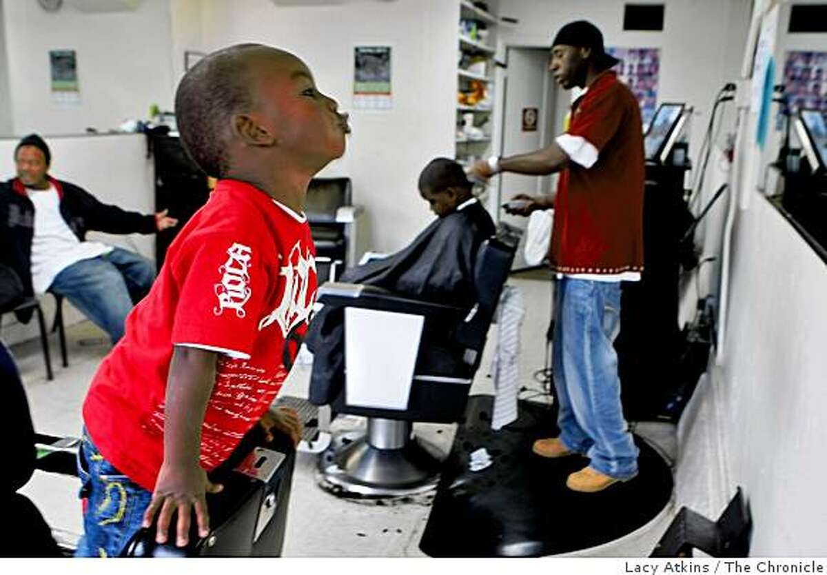 Terreon Hunt, 2 years old, makes faces in the mirror while Terrance Powell cuts Ahmaond Balls' hair on Wednesday Nov. 12, 2008, at The Shop in the Visiticion Valley district in San Francisco, Calif.