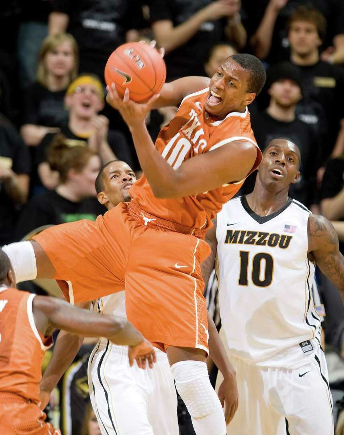 Texas' Jonathan Holmes, center, pulls down a rebound in front of Missouri's Ricardo Ratliffe, right, and Kim English, left, during the first half of an NCAA college basketball game Saturday, Jan. 14, 2012, in Columbia, Mo.