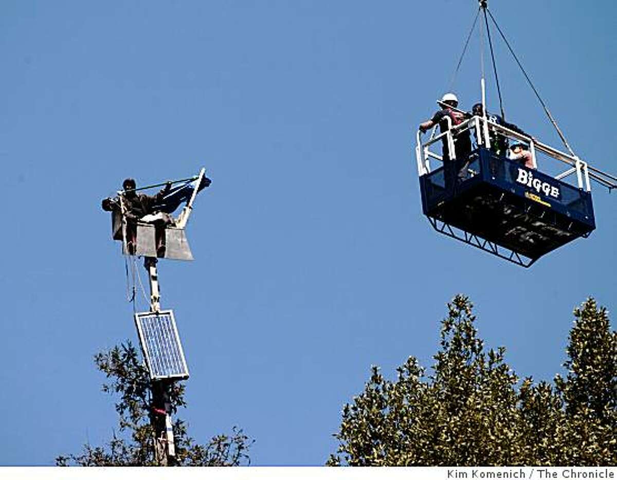 With resistance from the protesters, officials in a basket suspended from a construction crane begin to remove some of the equipment that tree-sitting protesters hauled up a redwood tree west of Memorial Stadium on the U. C, Berkeley campus in Berkeley, Calif., on Thursday, Aug. 21, 2008.