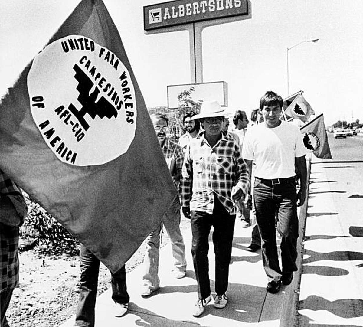 Cesar Chavez, in plaid shirt, marches with members of the United Farm Workers outside a Delano, Calif., supermarket in protest of the sale of products not harvested by their union, Aug. 25, 1975.