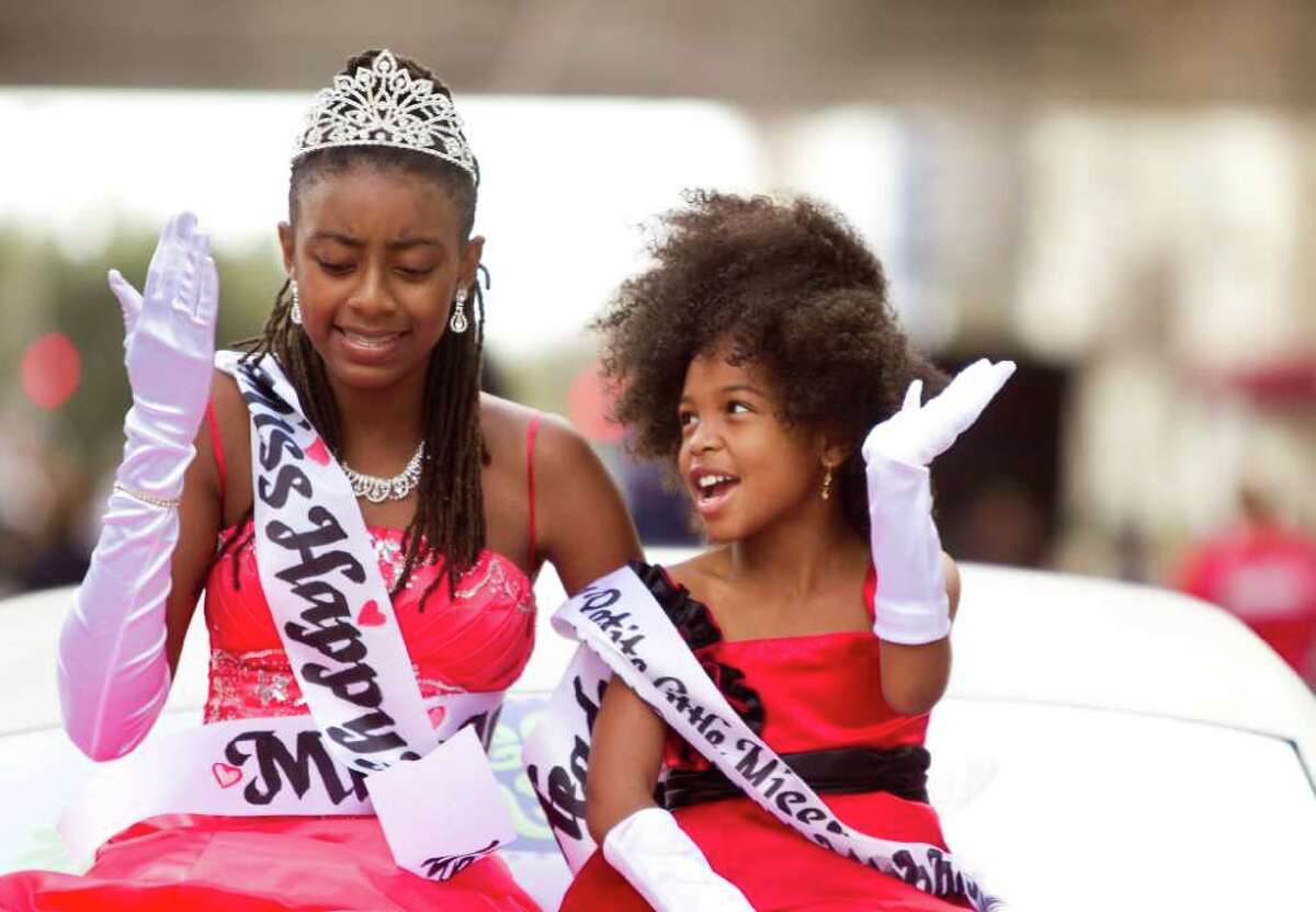 Tamirah Collins, 13, left, and Asha Malivers, 7, finalists of the Little Miss Happy Headed Natural Hair Pageant, talk as they wave and blow kisses to the crowd during the 34th Annual "Original" Dr. Martin Luther King Birthday Parade and Celebration Monday, Jan. 16, 2012, in Houston.
