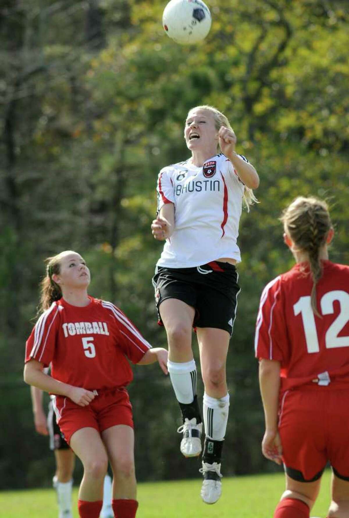 Fort Bend Austin senior midfielder Reagan Russell, center, goes up for a header in tournament play earlier this season.