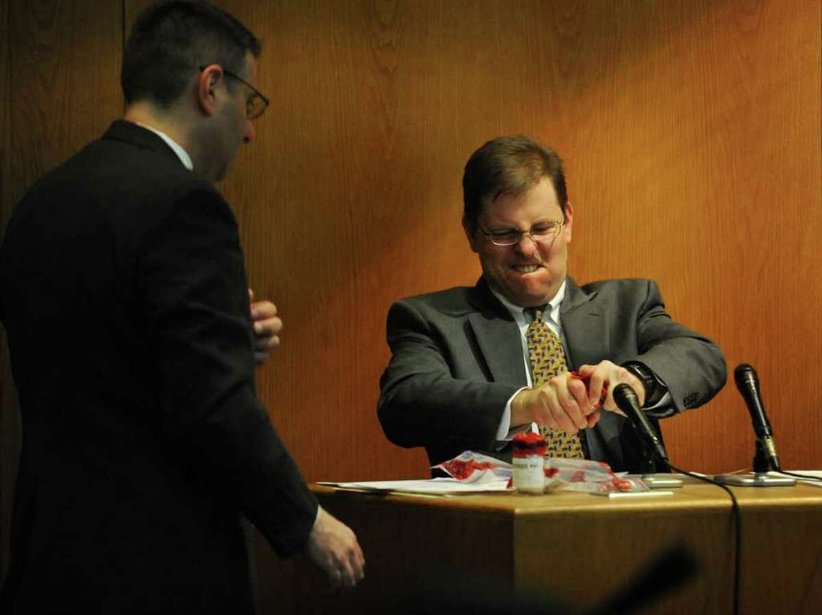 Frank Evangelista, right, struggles to open an exhibit containing one of two bullets that he removed from the body of deceased Fairfield jeweler Kim Donnelly, during day two of the Christopher DiMeo murder trial at Bridgeport Superior Court on Wednesday, January 19, 2011. At left is prosecuting Senior Assistant State's Attorney Joseph Corradino.