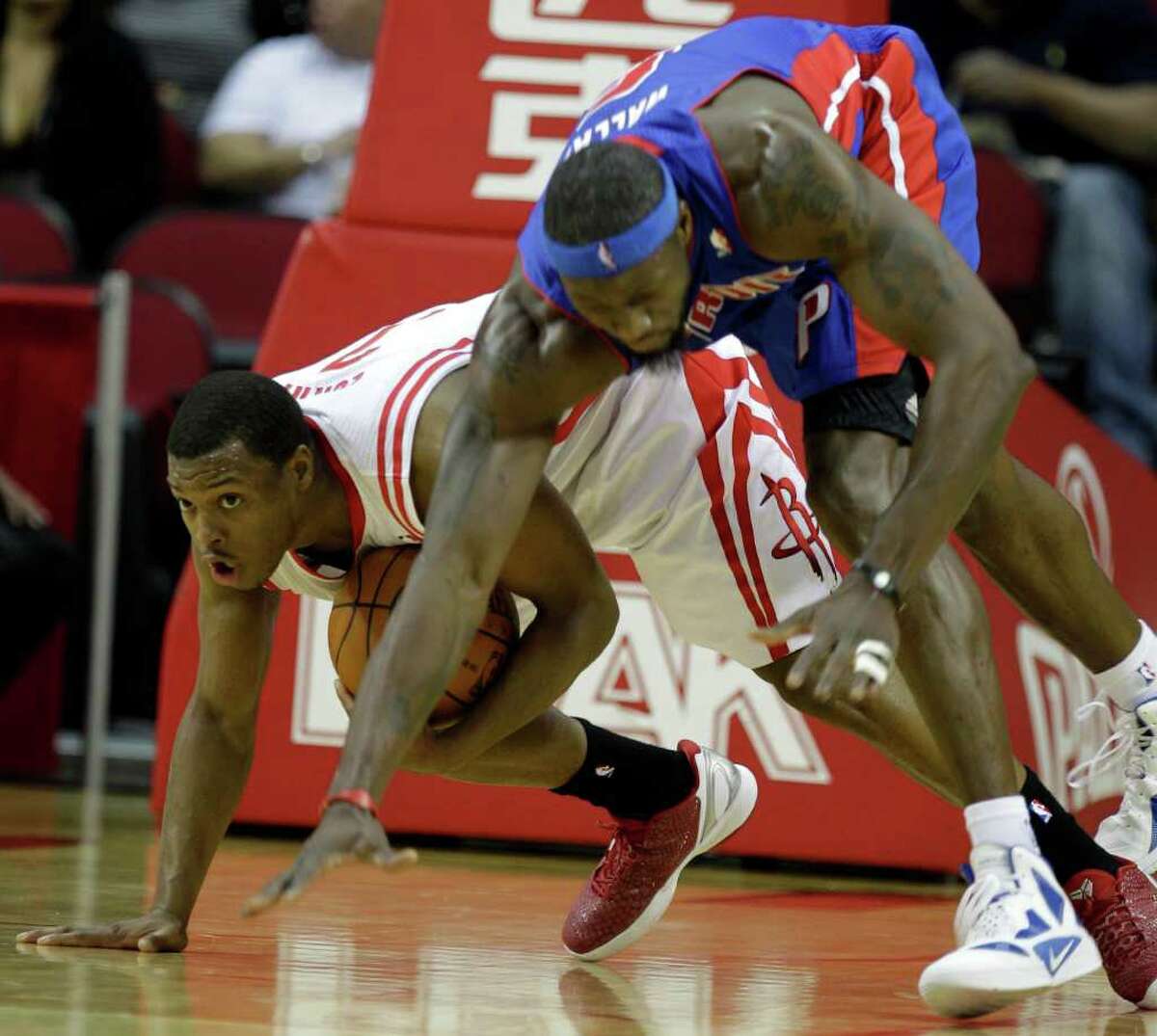 Houston Rockets' Kyle Lowry, left, and Detroit Pistons' Ben Wallace, right, tangle for the ball during NBA game at Toyota Center Tuesday, Jan. 17, 2012, in Houston.