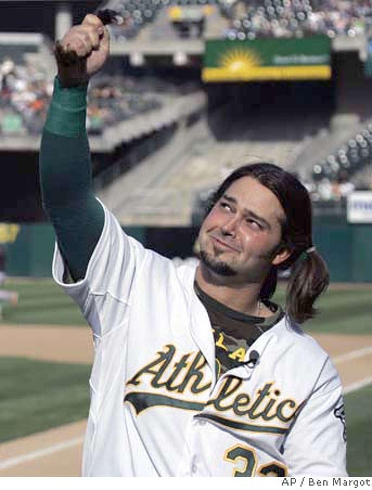 Oakland Athletics center fielder Nick Swisher holds his ponytail of hair cut at home plate by his father, former major league baseball player Steve Swisher, prior to the baseball game with the San Francisco Giants Saturday, May 19, 2007, in Oakland, Calif. Swisher had not cut his hair since the beginning of spring training, with the intention of donating his locks for a wig to be made for a woman with cancer, in honor of his grandmother who died of the illness. (AP Photo/Ben Margot)