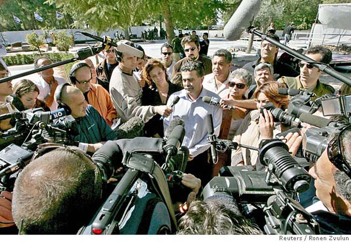Newly elected Labour Party leader Amir Peretz (C) speaks to reporters after laying a wreath at the late Yitzhak Rabin's gravesite in Jerusalem November 10, 2005. Peres was ousted as Israel's Labour Party leader on Thursday in an upset victory for a trade union chief whose vow to end a ruling alliance with Prime Minister Ariel Sharon could trigger early elections. REUTERS/Ronen Zvulun 0