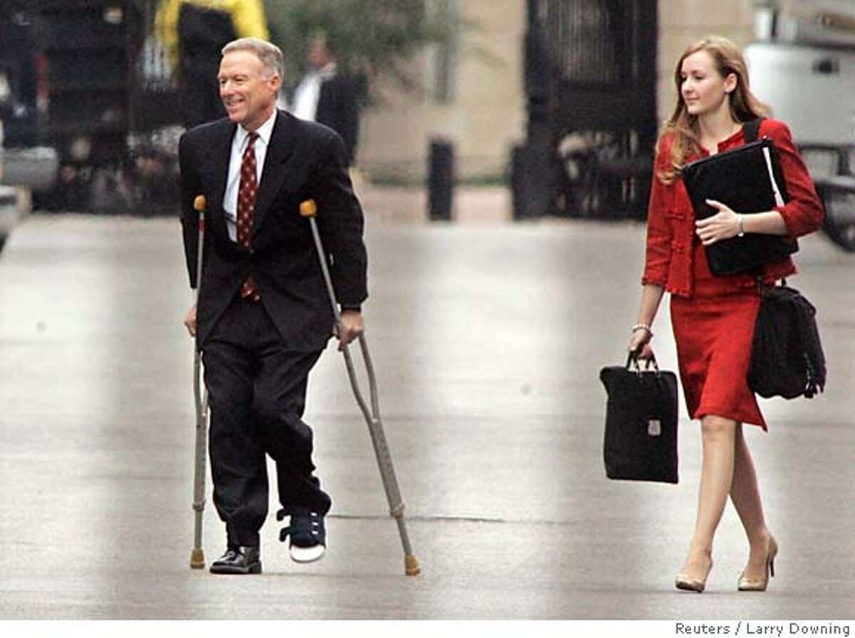 Vice President Dick Cheney's chief of staff Lewis 'Scooter' Libby walks out of the West Wing of the White House on crutches with an unidentified woman in Washington October 28, 2005. Libby, and other top White House officials braced for criminal charges on Friday from the federal grand jury investigating the leak of covert CIA operative Valerie Plame's identity. But legal sources said Fitzgerald has informed President George W. Bush's top political adviser, Karl Rove, will be spared indictment on Friday, although he will remain under investigation and in legal jeopardy. The picture was taken through a fence. REUTERS/Larry Downing