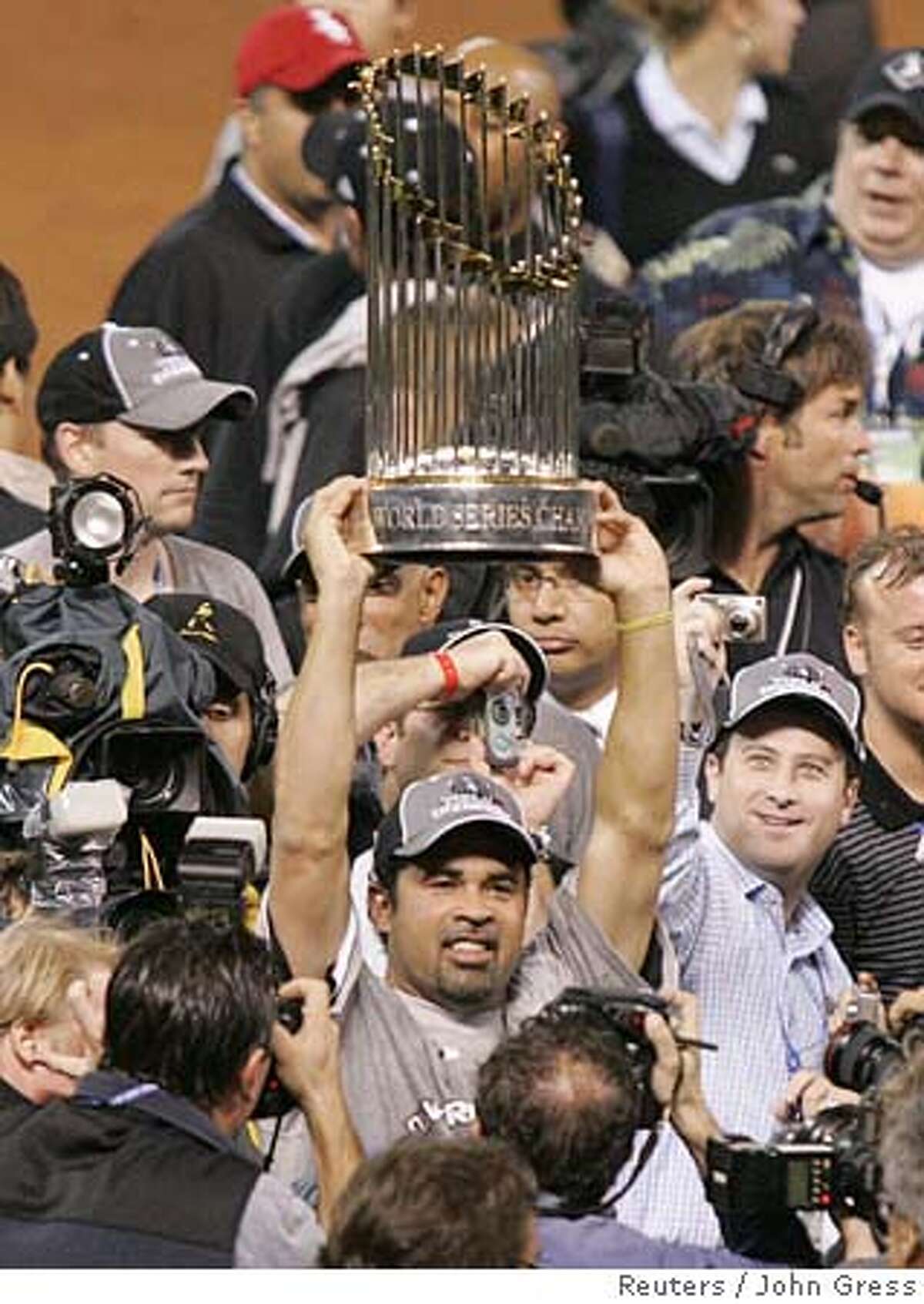 Chicago White Sox manager Ozzie Guillen holds up the World Series trophy during celebrations on the field after the White Sox defeated the Houston Astros 1-0 in Game 4 of Major League Baseball's 2005 World Series in Houston, Texas, October 26, 2005. The White Sox swept the Astros in four games and won their first World Series title since 1917. REUTERS/John Gress 0