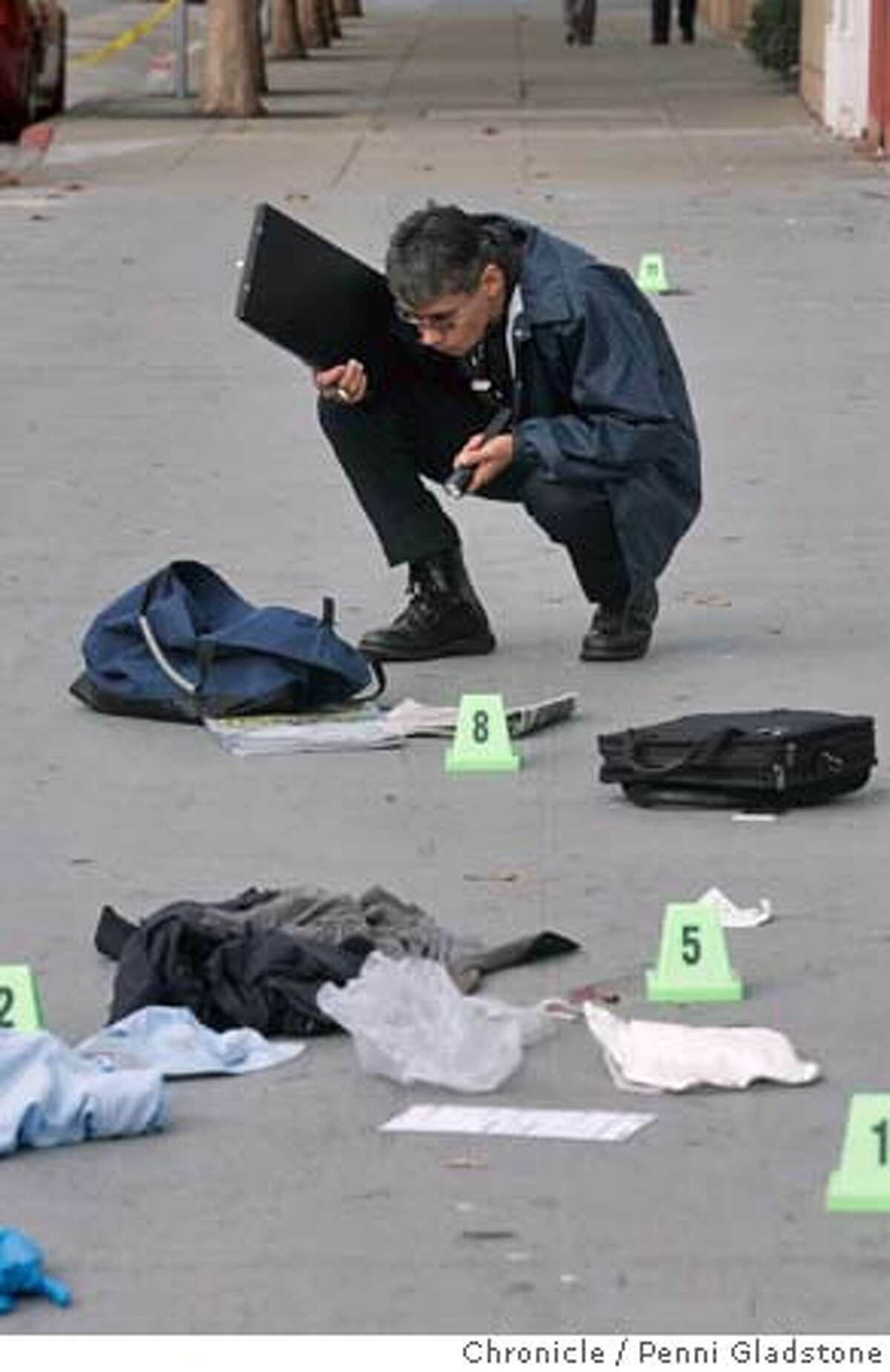 MURDER_0063_PG.JPG Crime Scene Investigator (CSI) Dave Kamita takes notes of victims things on the ground, uses his flashlight to see better. MURDER at Jackson and Polk. next to Lombardi's sporting goods. A person shot another then shot himself. San Francisco Chronicle, Penni Gladstone Photo taken on 10/27/05, in San Francisco,