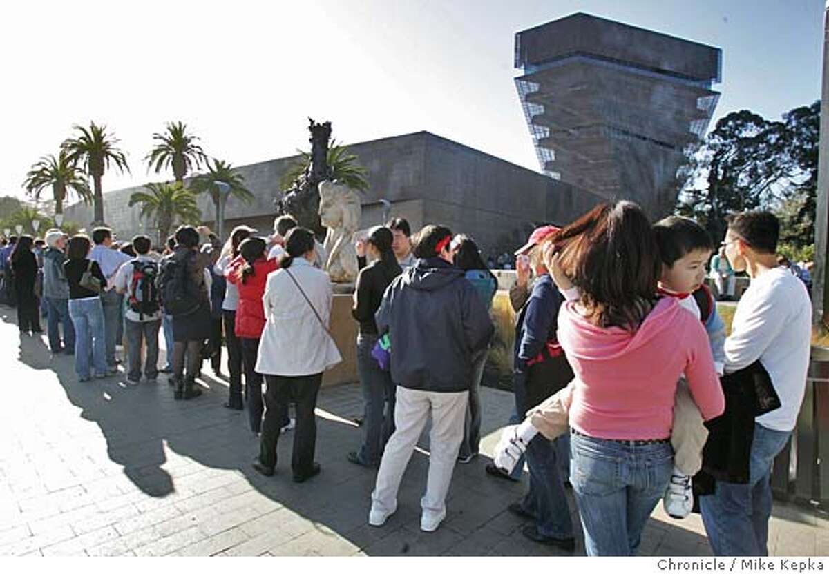 Timmy Dang held by his mother Gwen Ton, of San Francisco wait in a line that wrapped around the block to get into the De Young. The De Young opens its doors to the public for the first time since the completion of the new building. date} Mike Kepka / The Chronicle