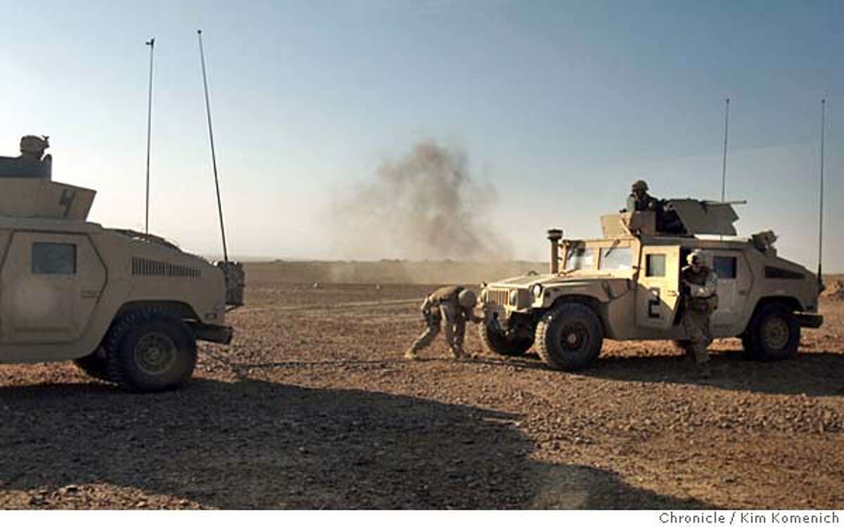 IRAQ01_BORDER_0014_KK.JPG Smoke from a mortar round that exploded a second earlier rises in the background as a Marine struggles to attach a tow chain that fell off his humvee. Another Marine jumps from the disabled humvee to help. Marines from the 1st Mobile Assault Platoon, Weapons Company, 3rd Battalion, 6th Marine Regiment wake from their desert bivouacs to discover they are being mortared from the nearby town of al Karabila They call in for air support and make a foray into town. San Francisco Chronicle Photo by Kim Komenich 9/30/05