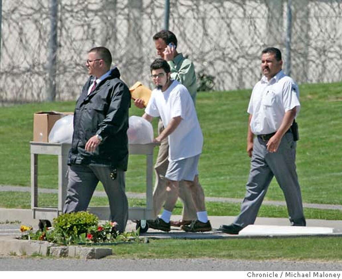 Flanked by two prison officials, Josh Wolf (center) pushes a cart full of his belongings (mostly books and letters) outside the gates to Federal Correctional Institution in Dublin. Behind him is one of his attorney's David Greene of the First Amendment Project who was there to pick Wolf up. Josh Wolf, a blogger and freelance journalist who has spent 7 1/2 months in federal prison for defying a grand jury subpoena related to his coverage of an anarchist protest, has turned over video footage to prosecutors and was released today, April 3, 2007 from the Federal Correctional Institution in Dublin. Photo by Michael Maloney / San Francisco Chronicle ***Josh Wolf, David Greene