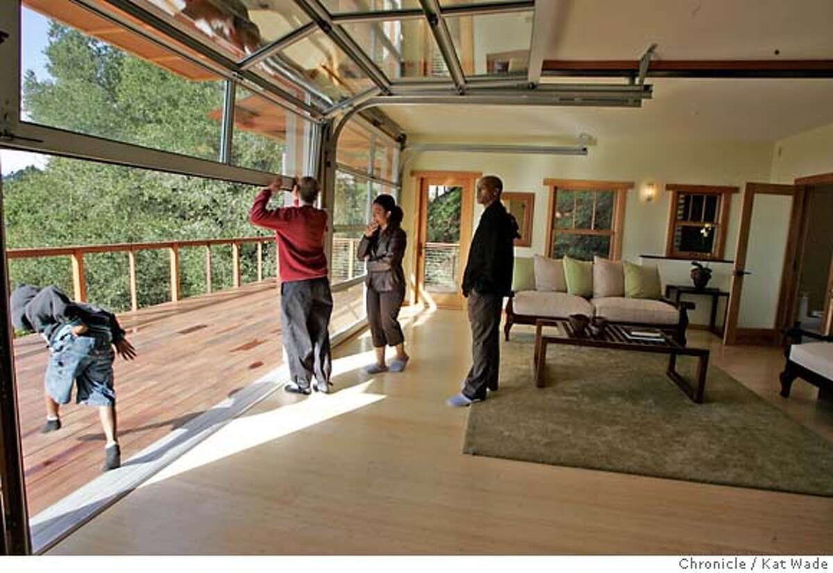 DIFFERENT25_165_KW.jpg (L to R) Brian Thian, 6, runs through the glass garage doors that lead to the deck of the spa level of the Japanese inspired home by designer/builder Sallie Lang, while Stacie Morrow, a design student and Robert Armstead look around the house during an open house on Sunday February 11, 2007. The Skyline Blvd. home, in Montclair, was built by a team of women. The eco-friendly home has sustainable bamboo floors. Kat Wade/The Chronicle Mandatory Credit for San Francisco Chronicle and photographer, Kat Wade, No Sales Mags out