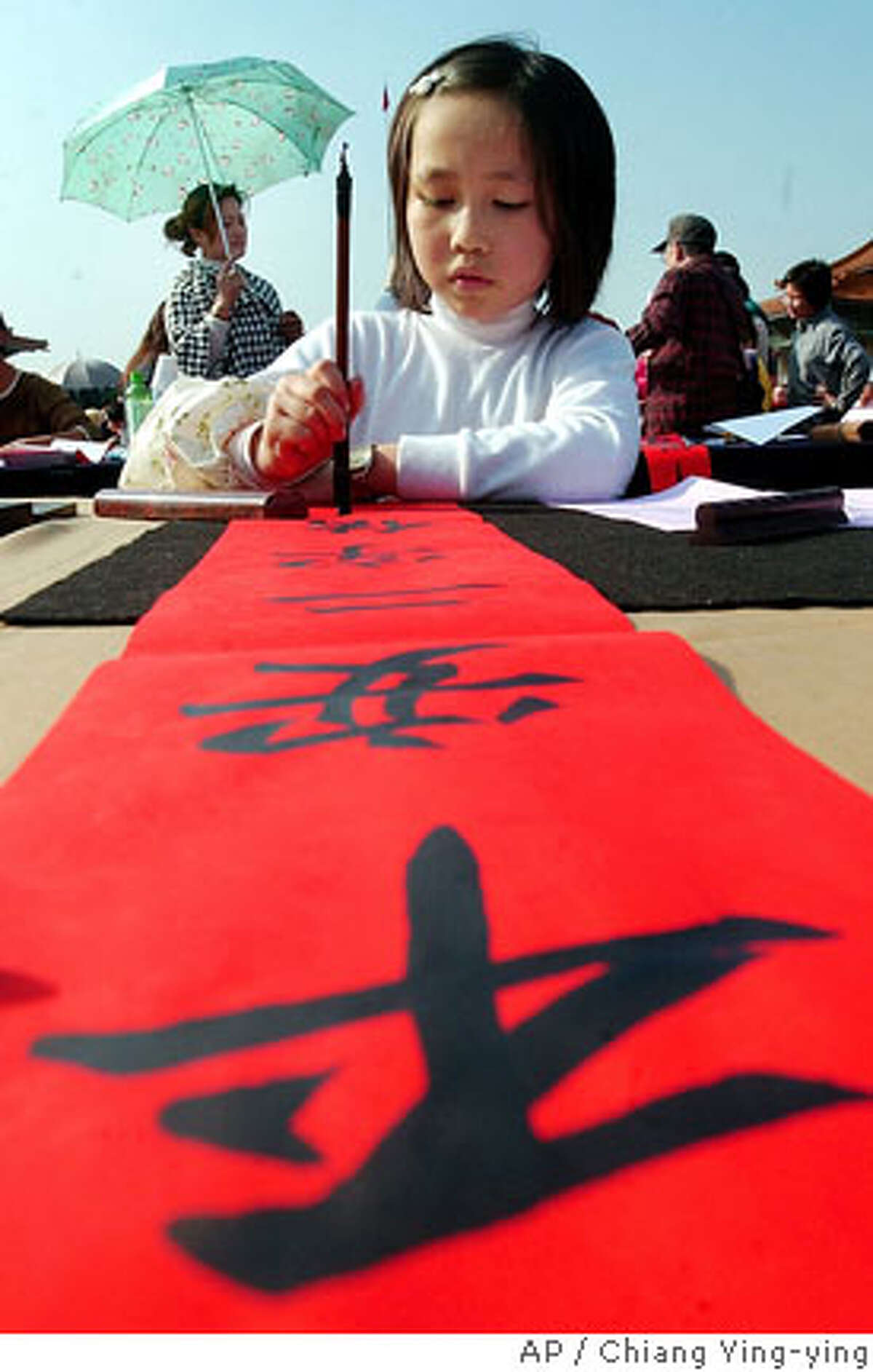 TRAVEL TAIWAN -- Taiwanese girl writes lucky words with hair brush during the activities for the upcoming Chinese New Year, Sunday, Feb. 4, 2007, in Taipei, Taiwan. Chinese New Year celebrations, according to the lunar calendar, falls on Feb. 18, and will commemorate the year of the pig. The characters partially read "Peace.," (AP Photo/Chiang Ying-ying)