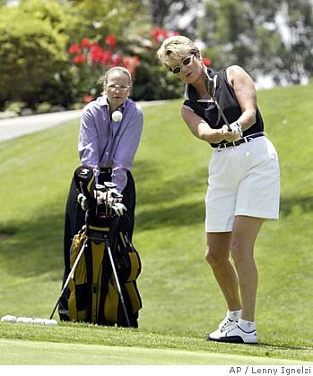 ** FILE ** Brigit Koebke pitches to a practice green at Bernardo Heights Country Club in San Diego, as her domestic partner, Kendall French, watches May 20, 2004. Deciding a case brought against the Country Club, the state's highest court said Monday that allowing the families of married members to golf gratis while charging the partners of gay members constitutes "impermissible marital status discrimination." The case was brought by Koebke, 48, an avid golfer who pays about $500 a month in membership fees. Koebke challenged a club policy allowing children, grandchildren and spouses of married members to play free, while her longtime partner, French, 43, could only play as a guest six times a year for up to $70 in greens fees. (AP Photo/Lenny Ignelzi)