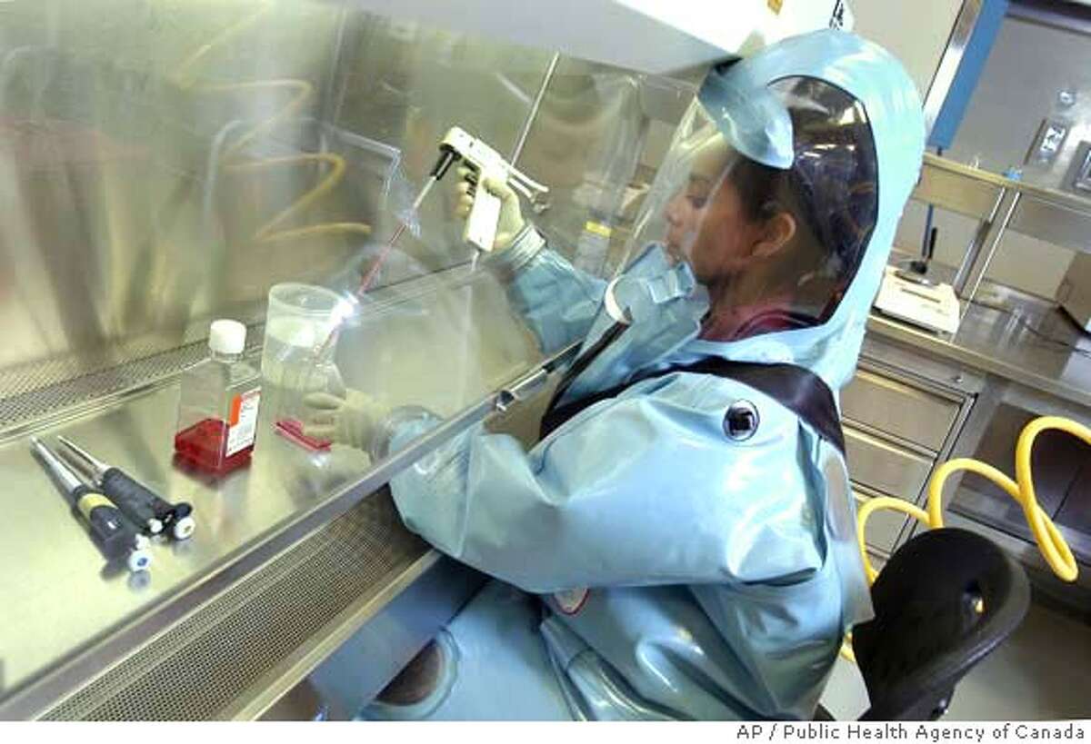 This 2006 photo provided by the Public Health Agency of Canada shows scientist Lisa Fernando working at a Biosafety Cabinet in the Public Health Agency of Canada's Level 4 containment laboratory in Winnipeg. Scientists at the laboratory said they were struck by how suddenly and overwhelmingly the 1918 flu struck seven macaques monkeys, intentionally infected with the resurrected virus and tested in the high-level biosafety lab. The virus spread faster than a normal flu bug and triggered a "storm" response in the animal's immune systems. Biosafety Cabinets provide primary containment, even in a Level 4 laboratory. (AP Photo/Public Health Agency of Canada) ** **