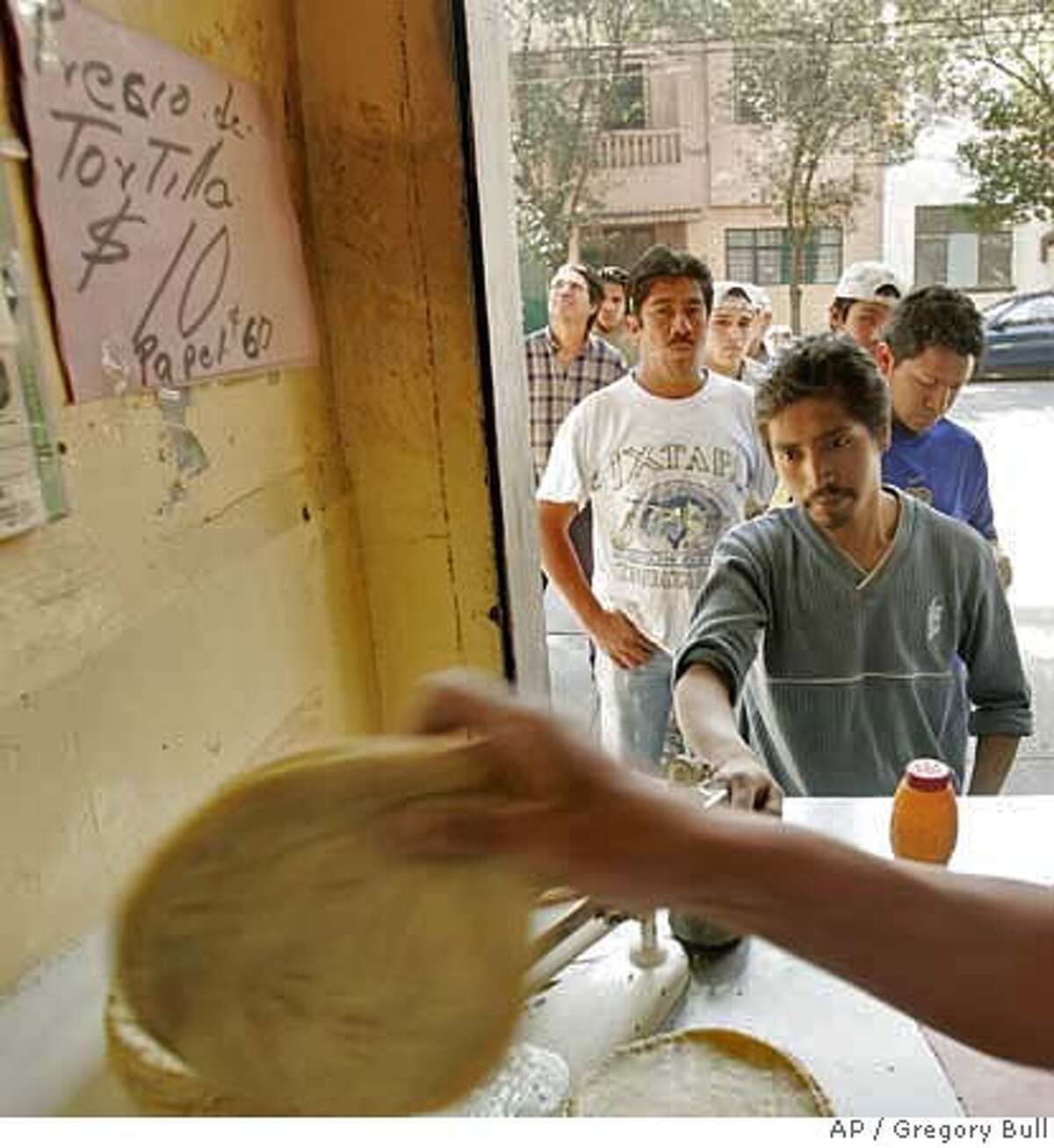 Men wait for tortillas at a tortilla shop in Mexico City, Mexico, Wednesday, Jan. 10, 2007. Tortillas, one of Mexico's most closely regulated commodities, rose in price this month, from seven to ten pesos for one kilo. (AP Photo/Gregory Bull) TO GO WITH STORY ON TORTILLA PRICES BY PETER ORSI EFE OUT