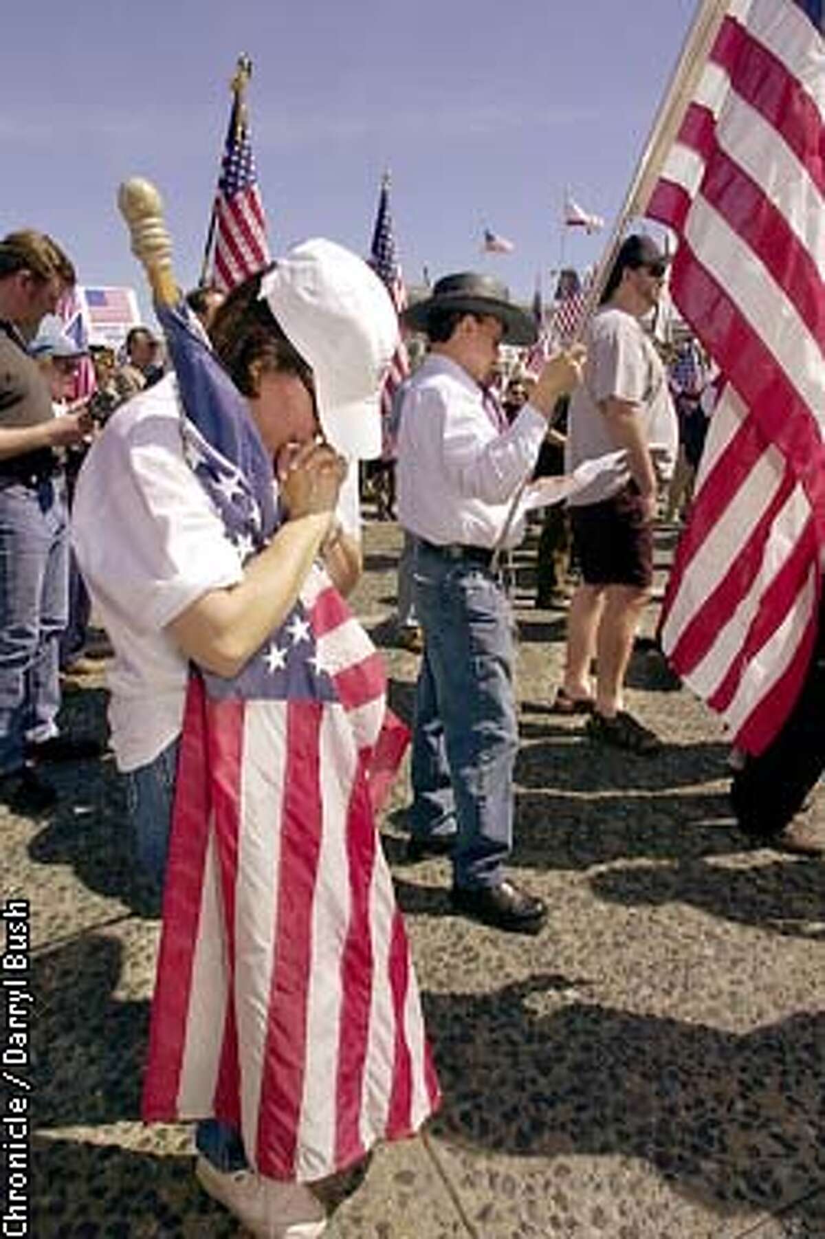 Barbara Mecham of San Carlos, prays while holding an American flag along with others attending a pro-troops rally held at Civic Center in San Francisco. Chronicle Photo by Darryl Bush