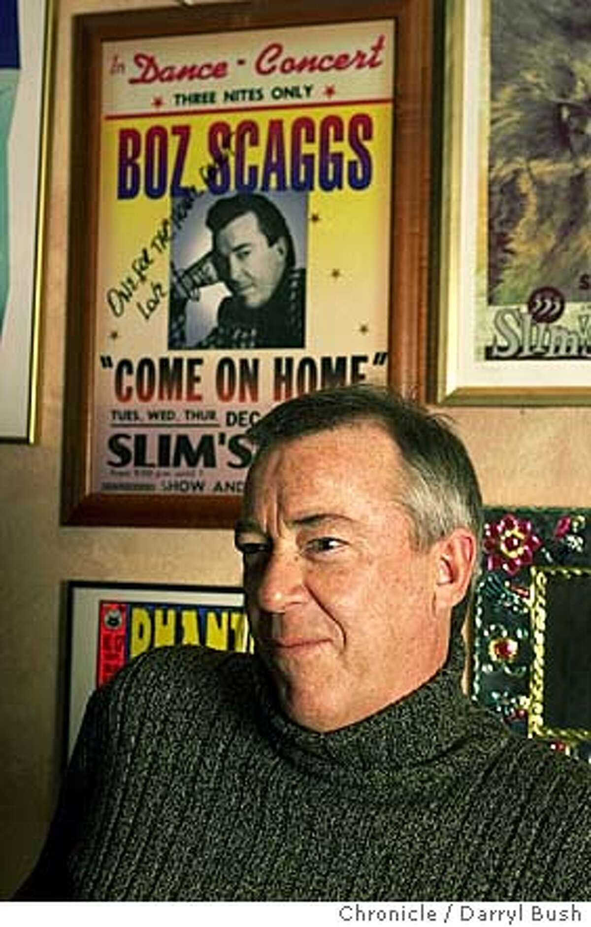 Boz Scaggs with a poster of concert he played in the background, inside the basement office of Slim's nightclub in San Francisco. Chronicle Photo by Darryl Bush