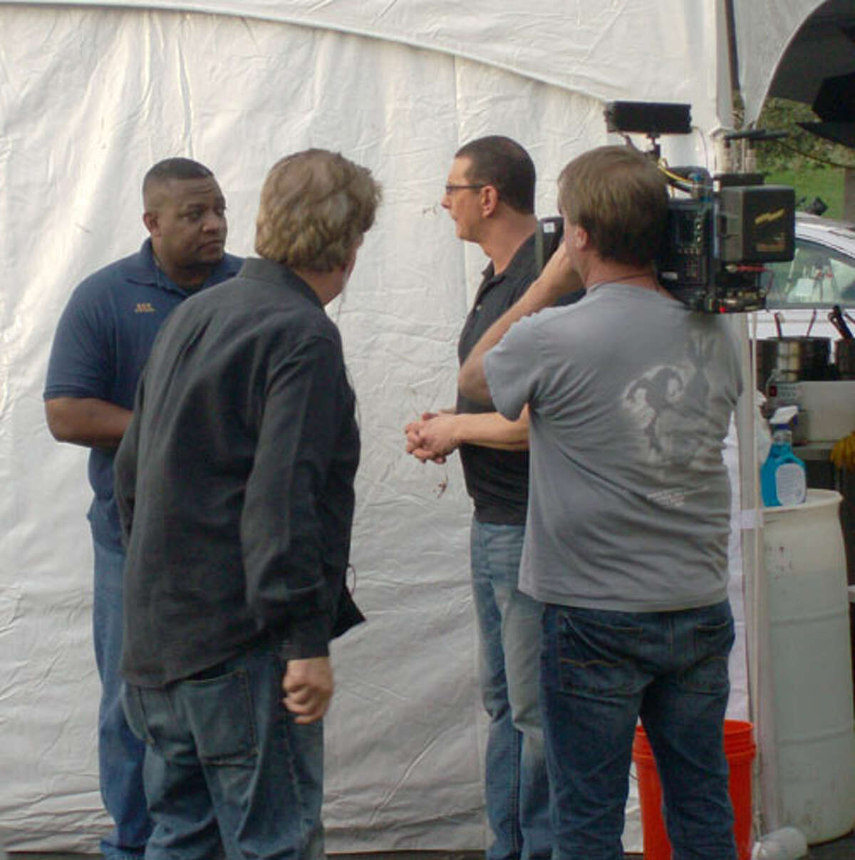 Mama Lee’s Soul Food restaurant owner Ken Lee (far left) listens to advice from TV celebrity chef Robert Irvine (rear right) Monday as television crew members tape the exchange for broadcast on Irvine’s “Kitchen Impossible” television show. Photo by Michele Gwynn