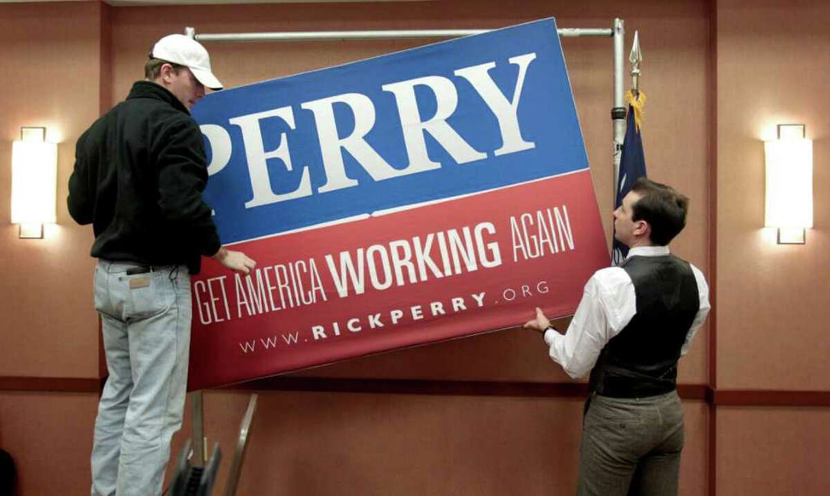 Campaign workers Ryan Vise, left, and Lucas Baiano remove a sign following a news conference in North Charleston, S.C., Thursday, Jan. 19, 2012, where Republican presidential candidate Texas Gov. Rick Perry announced he is suspending his campaign and endorsing Newt Gingrich.