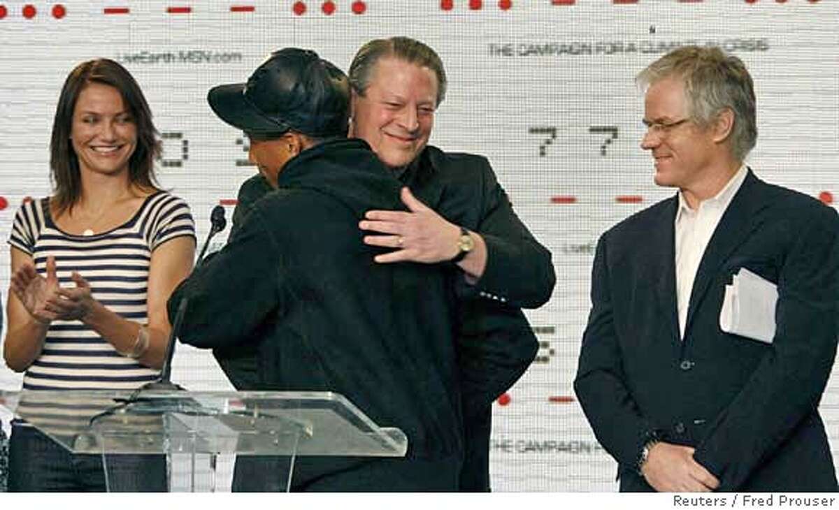 Producer and singer Pharrell Williams (C) is hugged by former U.S. vice president Al Gore, as actress Cameron Diaz (L) and producer Kevin Wall attend a news conference for the 'Live Earth' concerts in Los Angeles, California February 15, 2007. The planned July 7, 2007 concerts will take place in Sydney, Johannesburg, London and other cities to mobilize action to stop global warming. REUTERS/Fred Prouser (UNITED STATES)