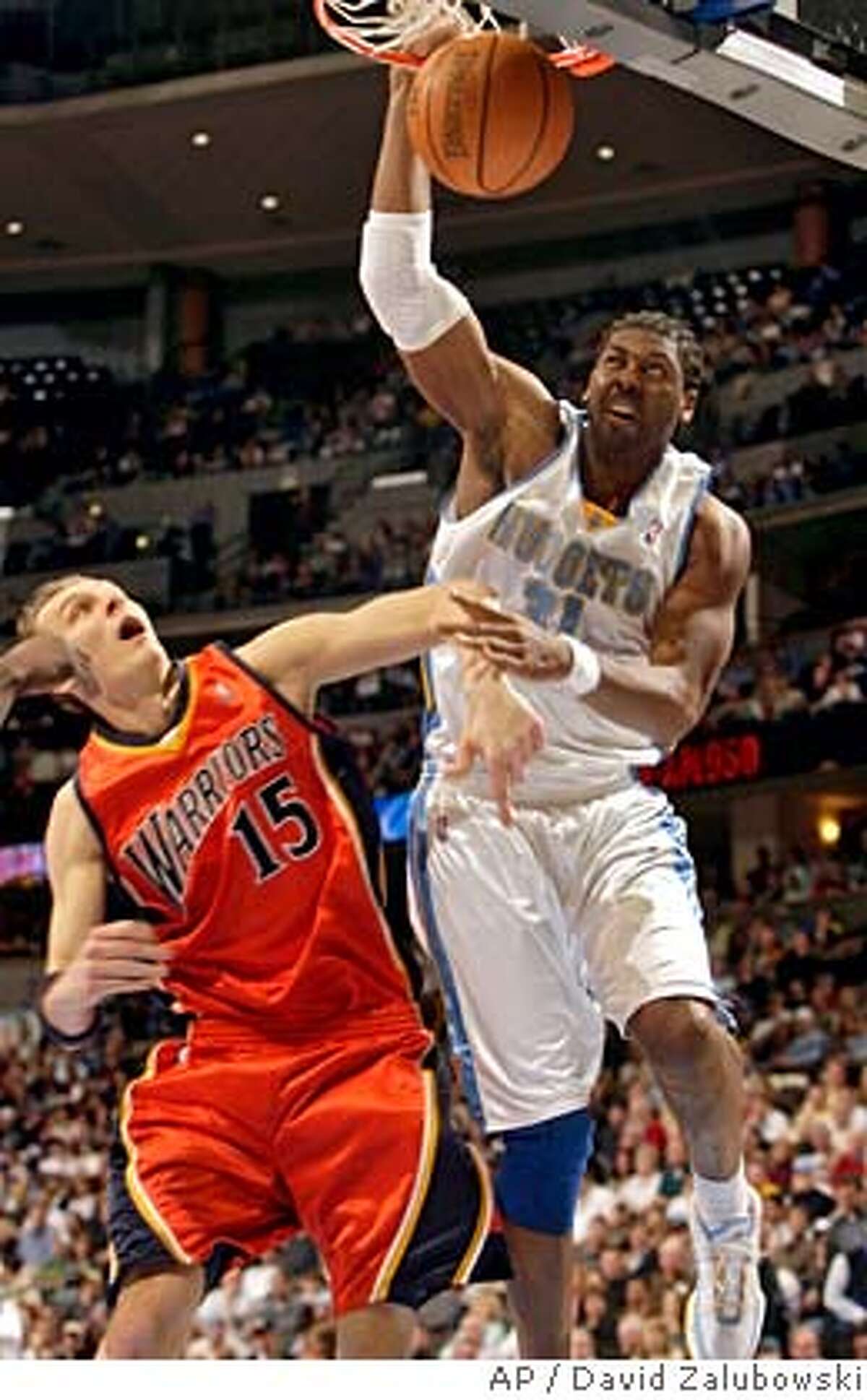 Denver Nuggets forward Nene, right, of Brazil, dunks the ball for a basket over Golden State Warriors center Andris Biedrins, of Latvia, in the third quarter of the Nuggets' 123-111 victory in an NBA basketball game in Denver on Monday, Feb. 12, 2007. (AP Photo/David Zalubowski)