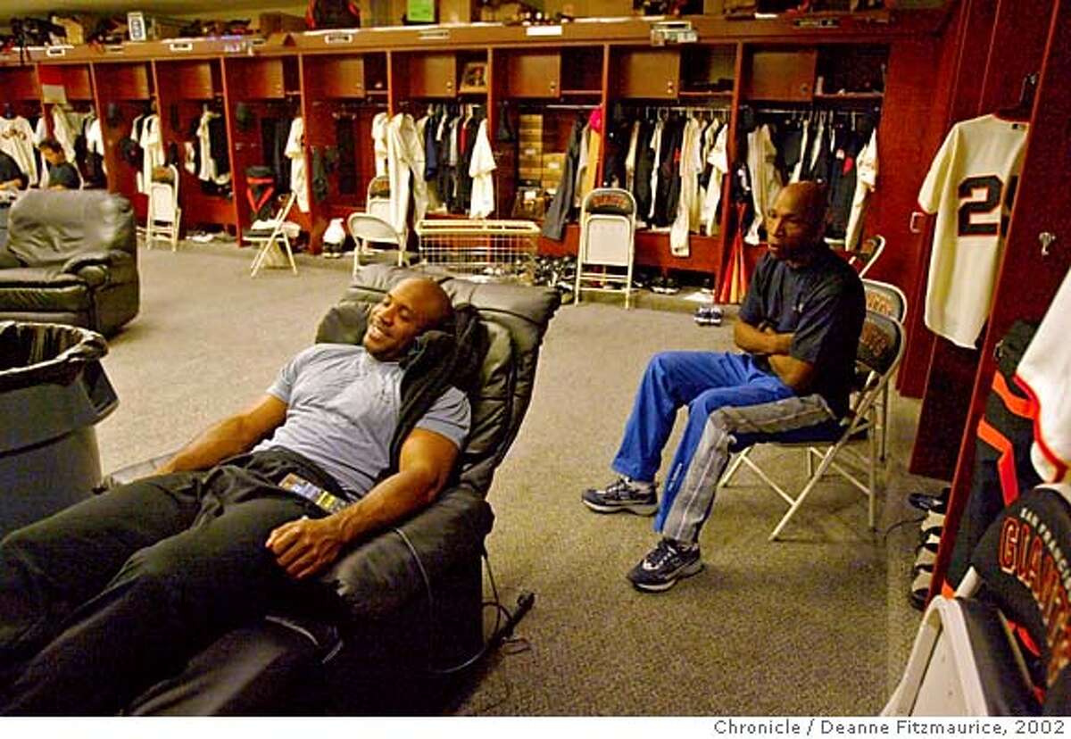 BONDS8-C-05AUG02-SP-DF Barry Bonds relaxes in his reclining chair in the San Francisco Giants clubhouse before a game at Pacific Bell Park. Behind him is one of his trainers, Harvey Shield. Bonds is two homeruns away from 600 career homeruns. CHRONICLE PHOTO BY DEANNE FITZMAURICE CAT