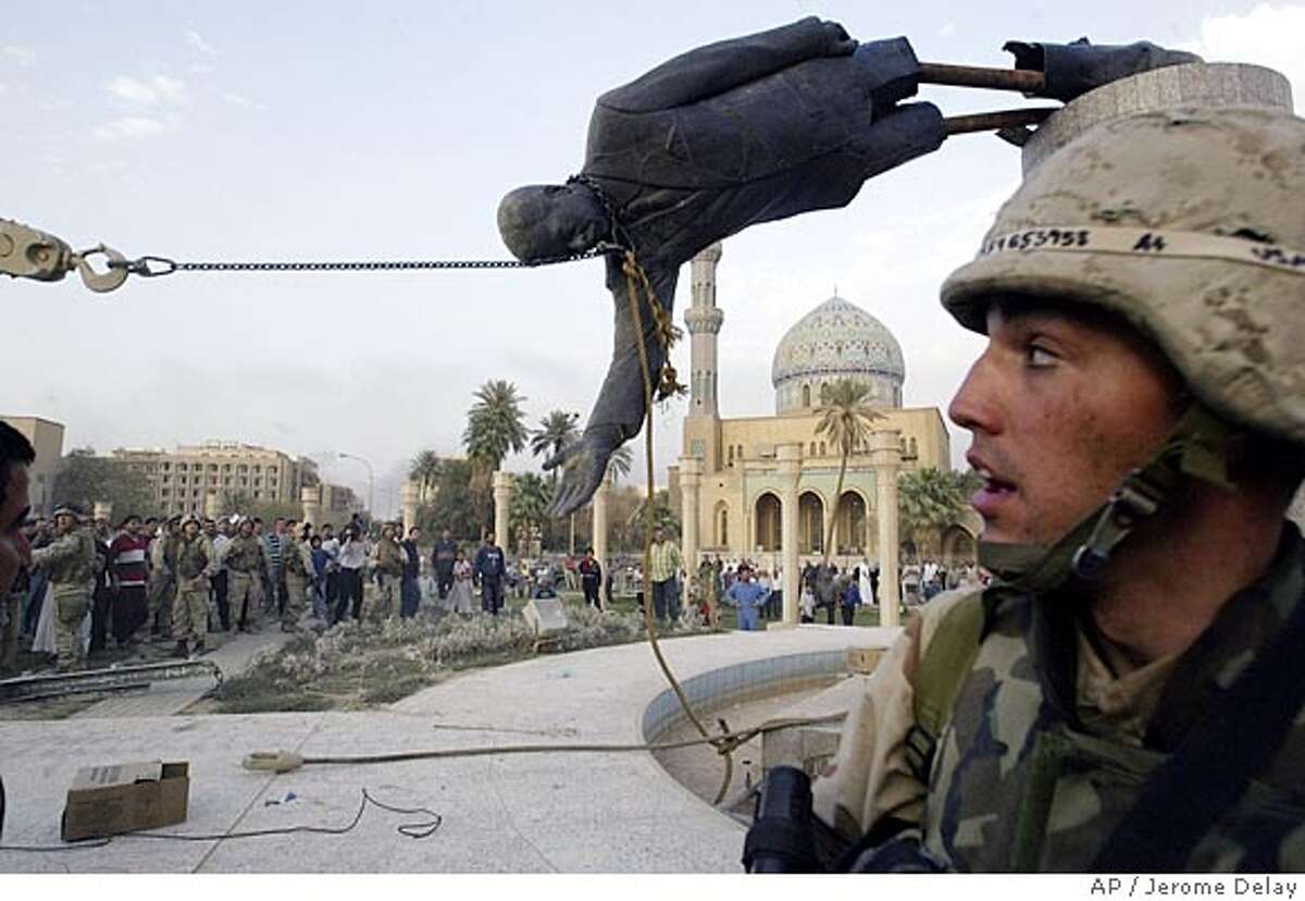 Iraqi civilians and U.S. soldiers pull down a statue of Saddam Hussein in downtown Baghdad Wednesday April 9, 2003. (AP Photo/Jerome Delay)