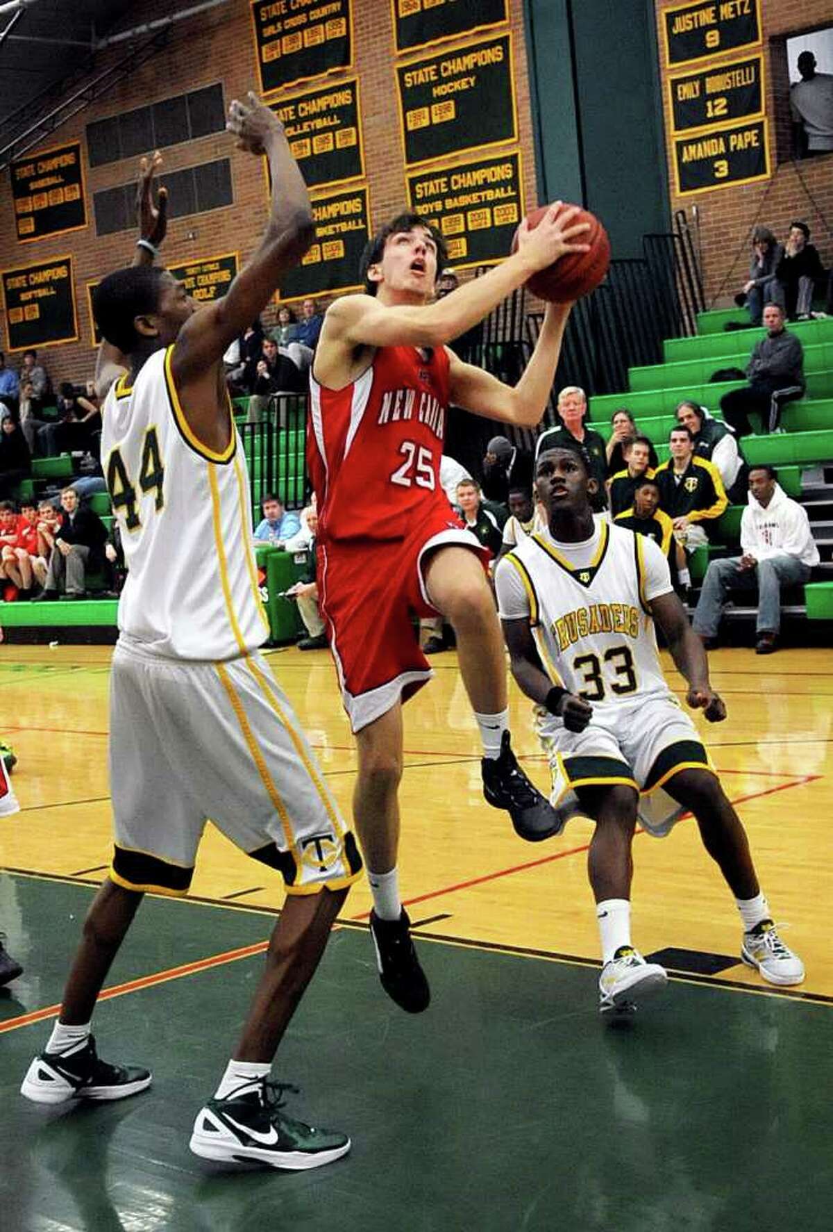 New Canaan's Chris Dewaele puts up a shot as he is defended by Trinity Catholic's Paschal Chukwu, left, and Kevin Leumene, right, during Friday's game in Stamford on January 20, 2012.