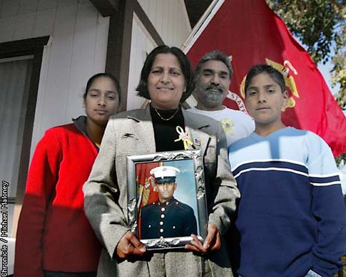 Jagdeep Grewal holds a portrait of her 21 year old son Marine Lance Corporal Apinderjit Grewal Jr. who is fighting in Iraq. Next to her from left is daughter Navdeep Grewal (17), husband Apinderjit Grewal and son Raj Grewal (13). They are standing on the porch of their Burlingame home in front of a Marine Corps flag. All were out this last weekend attaching yellow ribbons to signs and trees in Burlingame. The yellow ribbons have been placed on city light poles throughout Burlingame by the Grewals and friends to show support for the troops. It's against a city ordinance however the Burlingame city council is looking the other way drawing some complaints. CHRONICLE PHOTO BY MICHAEL MALONEY