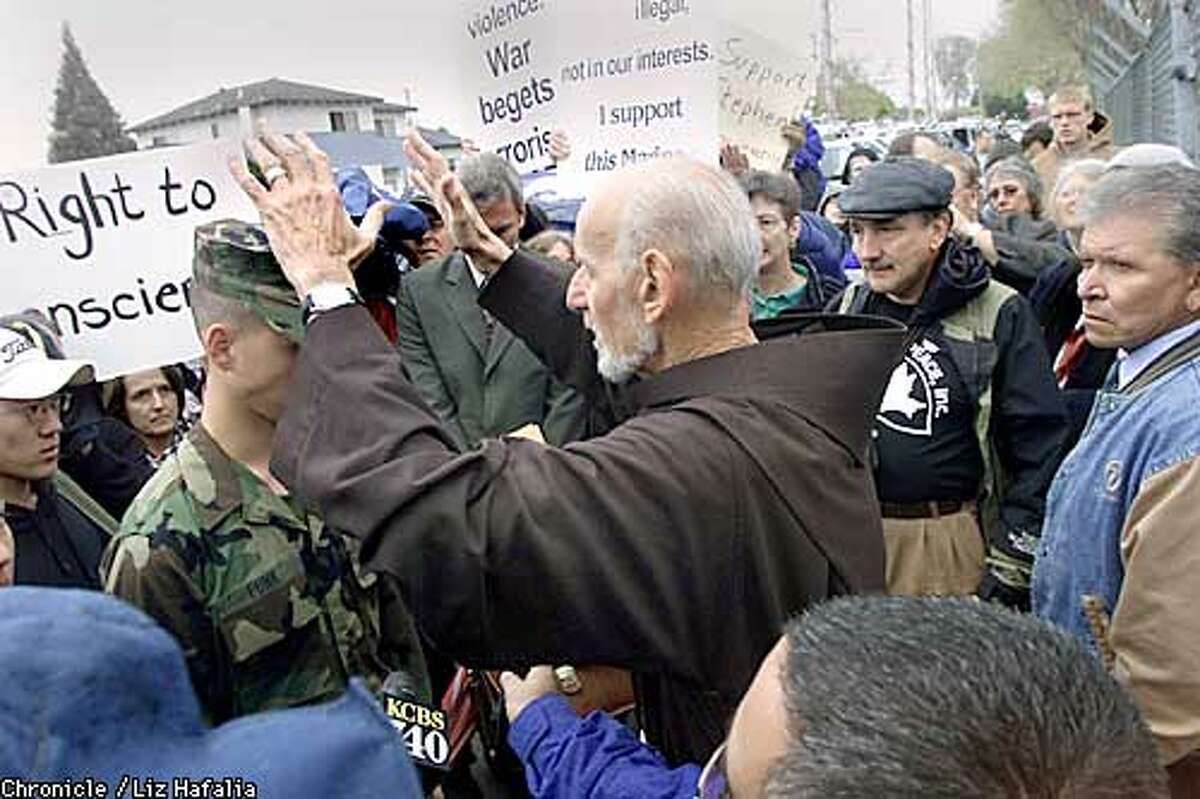 Stephen Funk, a volunteer reservist with the U.S. Marine Corps, gets blessed by father Lewis Vatale of St. Boniface/San Francisco before he enters the gates of 1st Beach Terminal Operations, 4th Landing Support Battalion in San Jose. He is publicly declaring his conscientious objector status. (PHOTOGRAPHED BY LIZ HAFALIA/THE SAN FRANCISCO CHRONICLE)