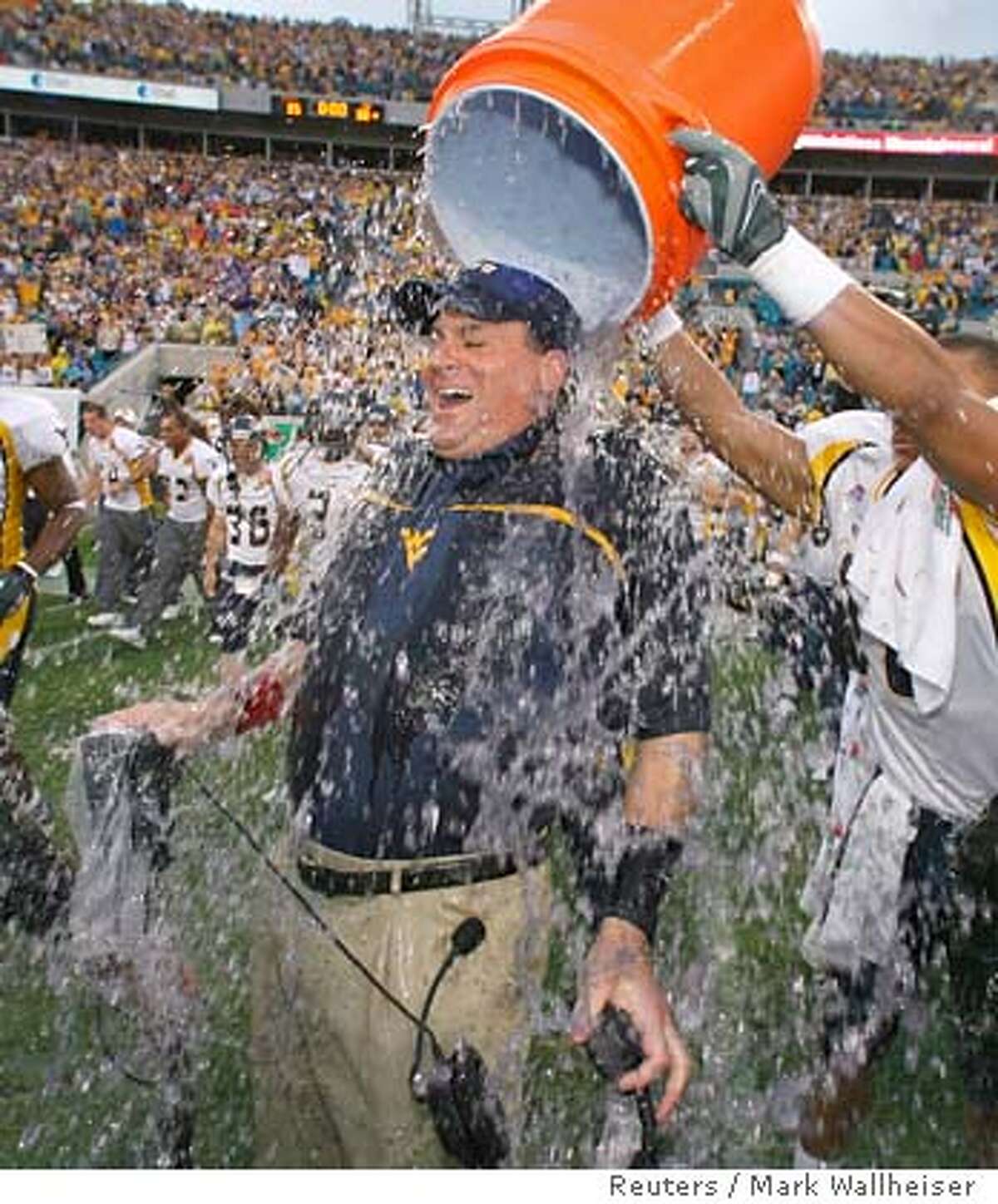 West Virginia tailback Steve Slaton (R) dunks ice water on Mountineer head coach Rich Rodriguez after he led his team to a 38-35 victory over the Georgia Tech Yellow Jackets in the Gator Bowl game at Alltel Stadium in Jacksonville, Florida January 1, 2007. REUTERS/Mark Wallheiser (UNITED STATES)