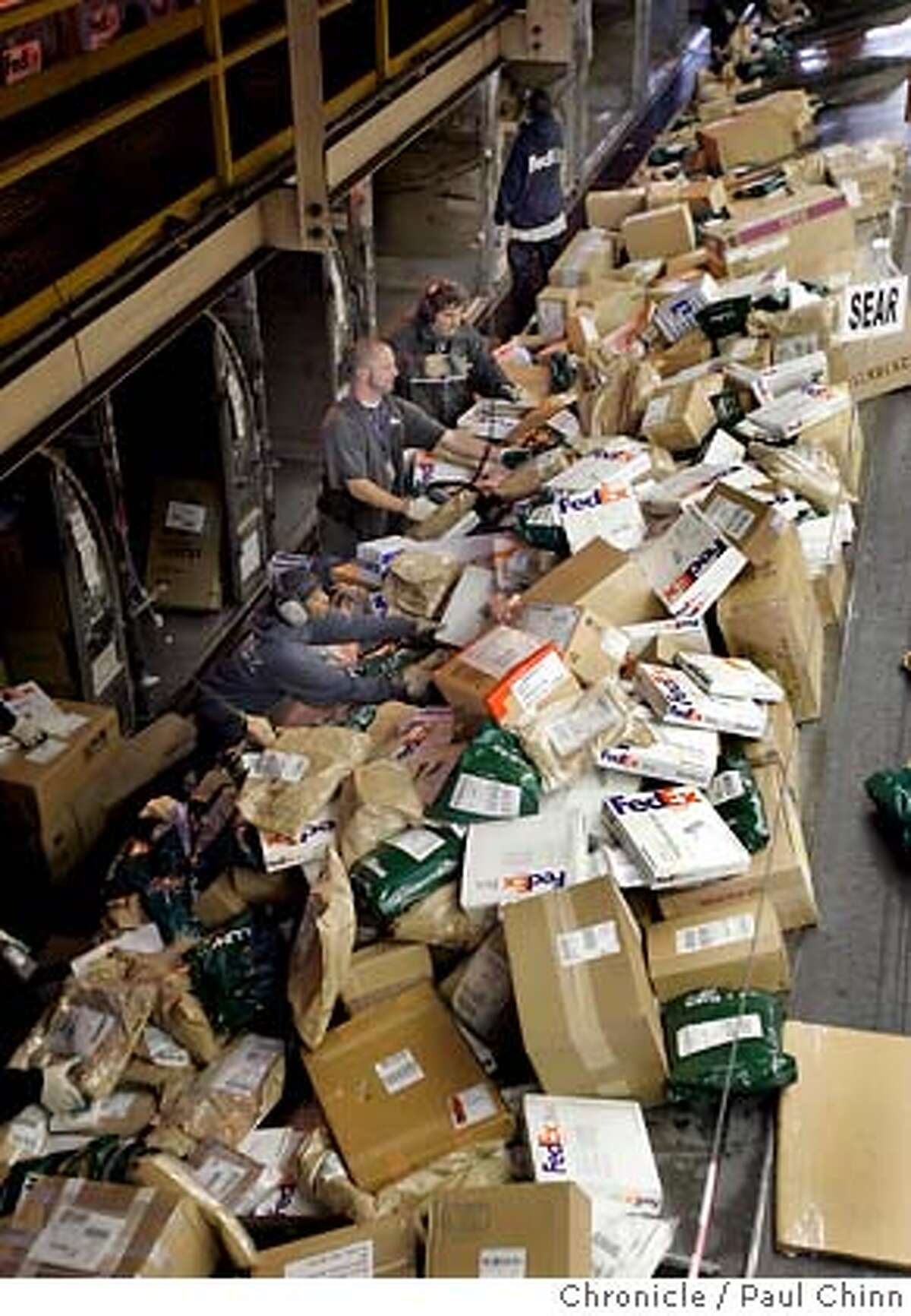 fedex21_084_pc.jpg Sorters wade through a mountain of parcels. The Federal Express sorting facility at Oakland International Airport on 12/17/04 in Oakland, CA. PAUL CHINN/The Chronicle MANDATORY CREDIT FOR PHOTOG AND S.F. CHRONICLE/ - MAGS OUT